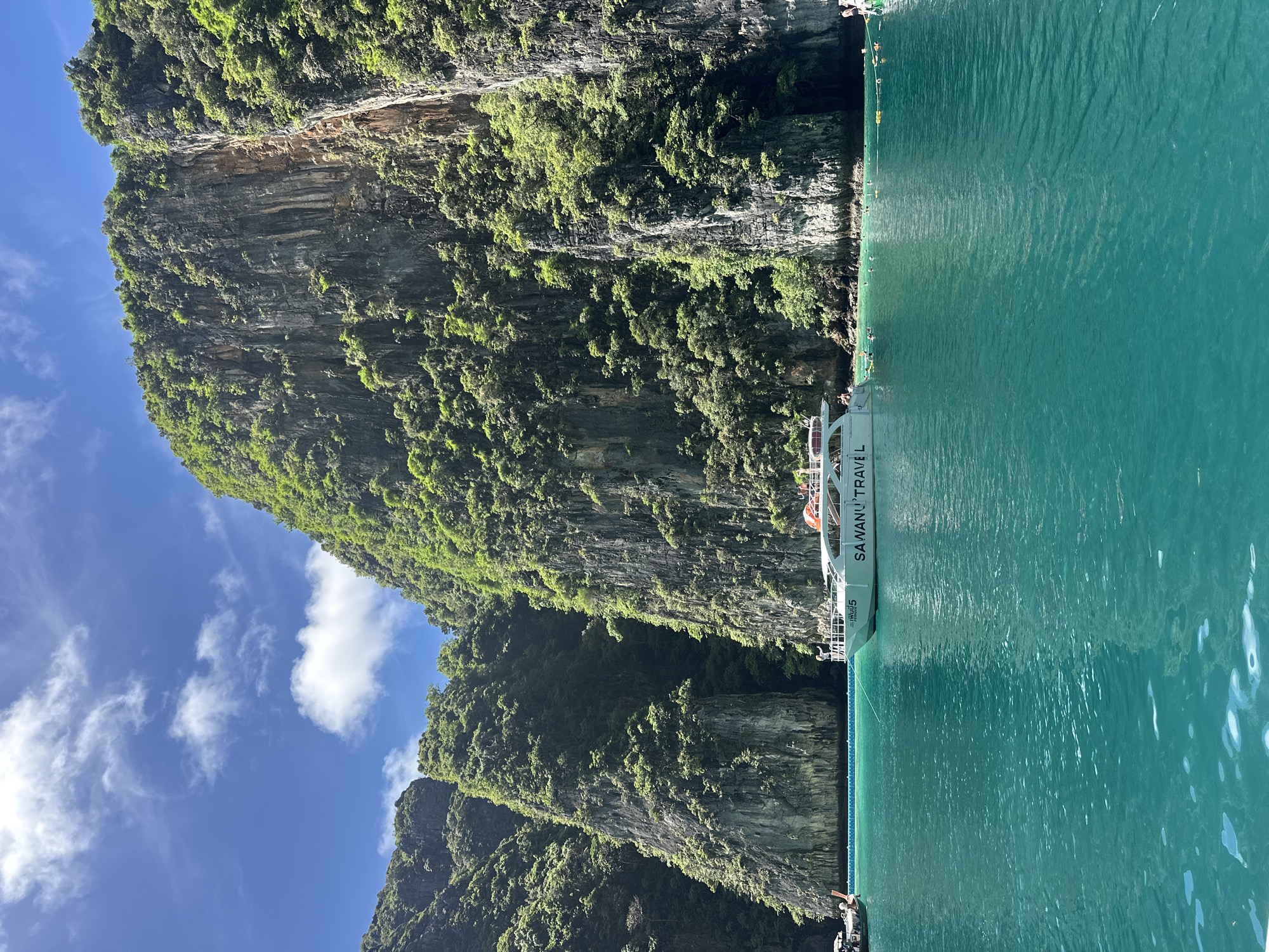 Boats navigate turquoise waters below Phi Phi Islands' limestone cliffs
