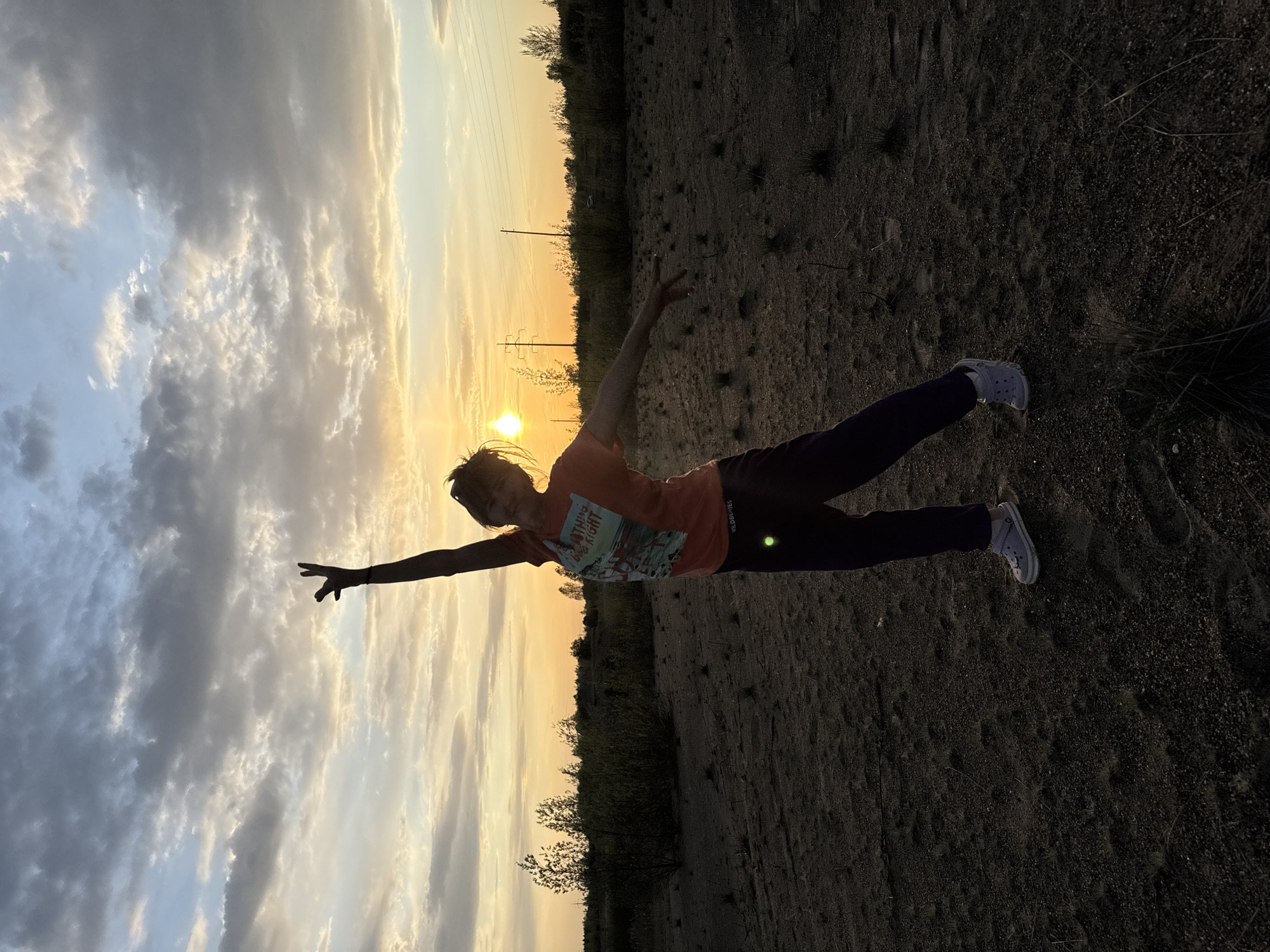 Woman strikes playful poses in Russian field at sunset