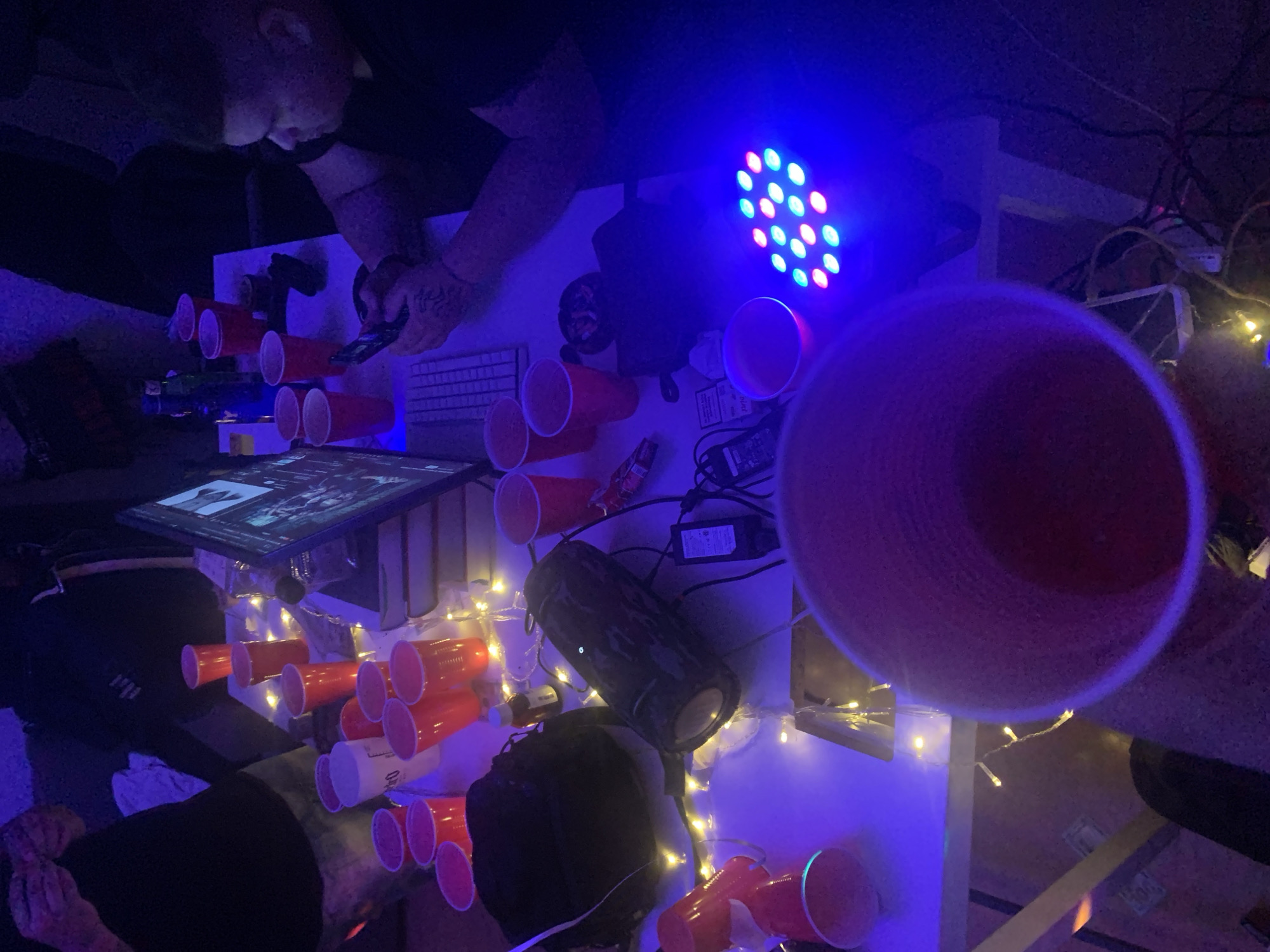 Cluttered desk with red cups and electronics documented