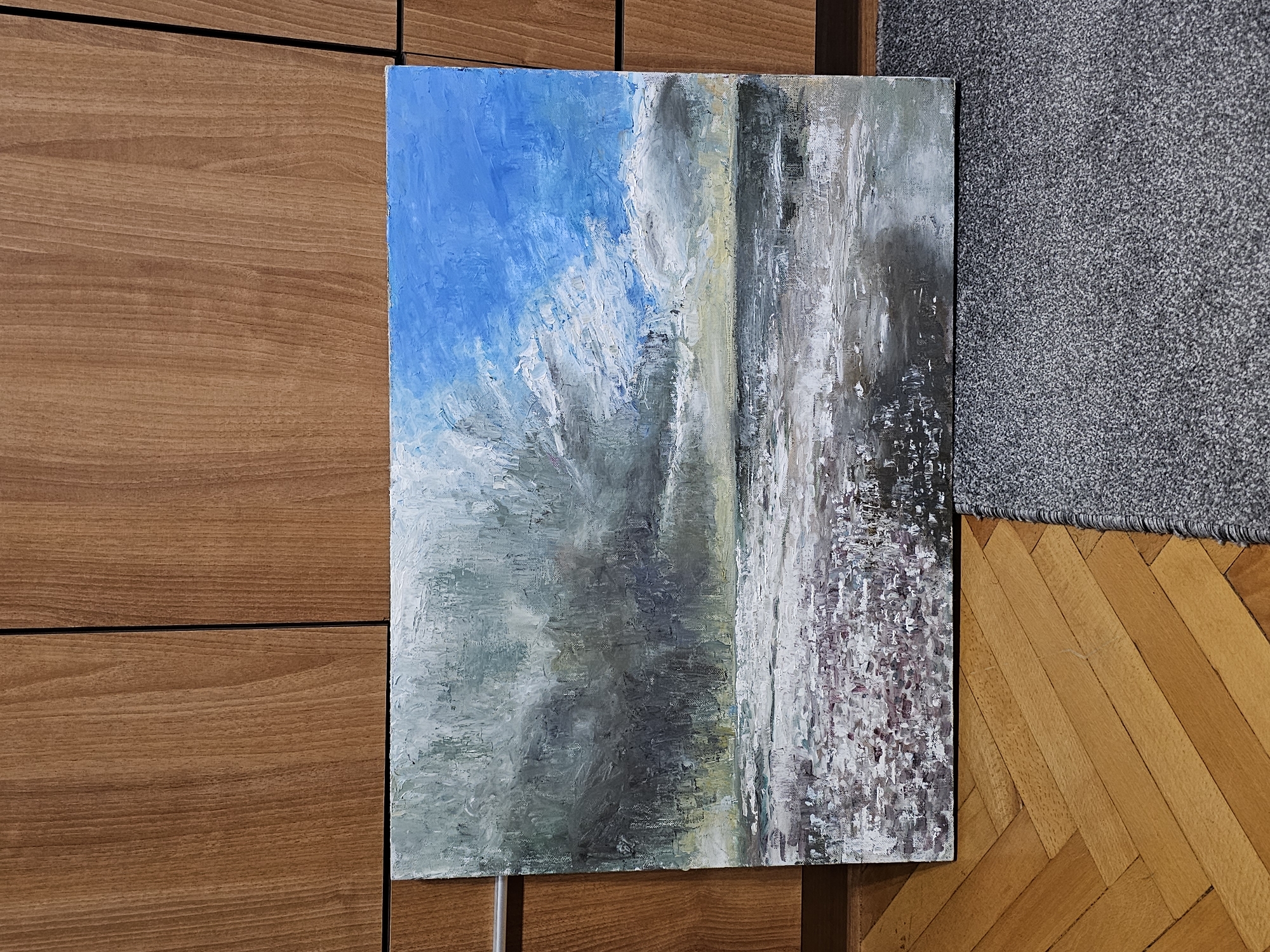 Oil painting with sky and landscape observed against wooden wall