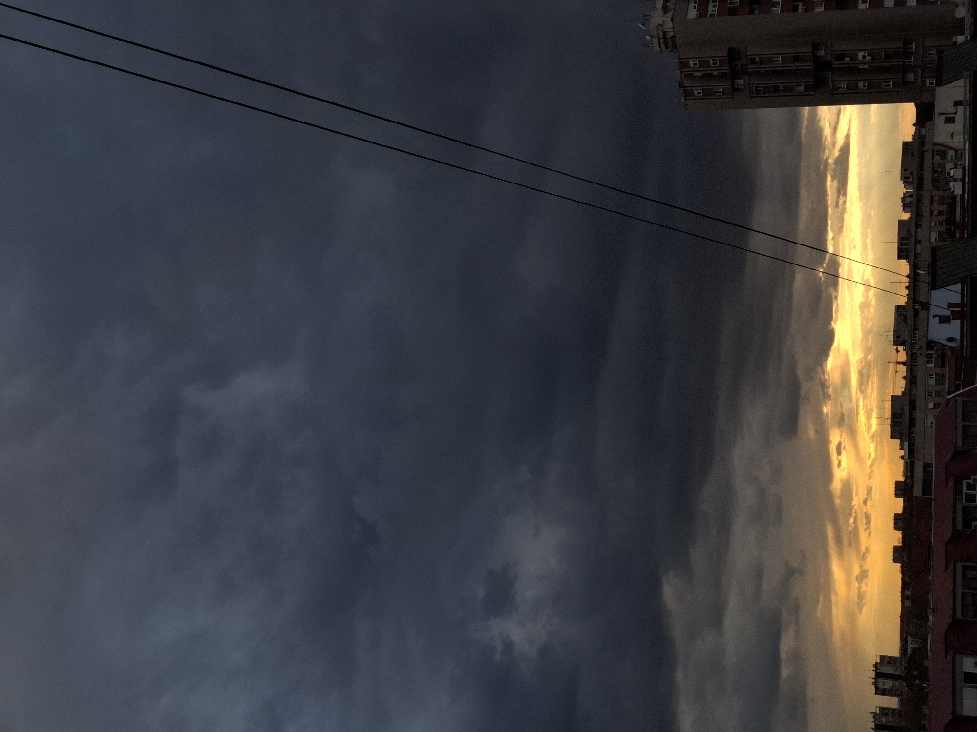 Dramatic storm clouds contrast with golden horizon over city
