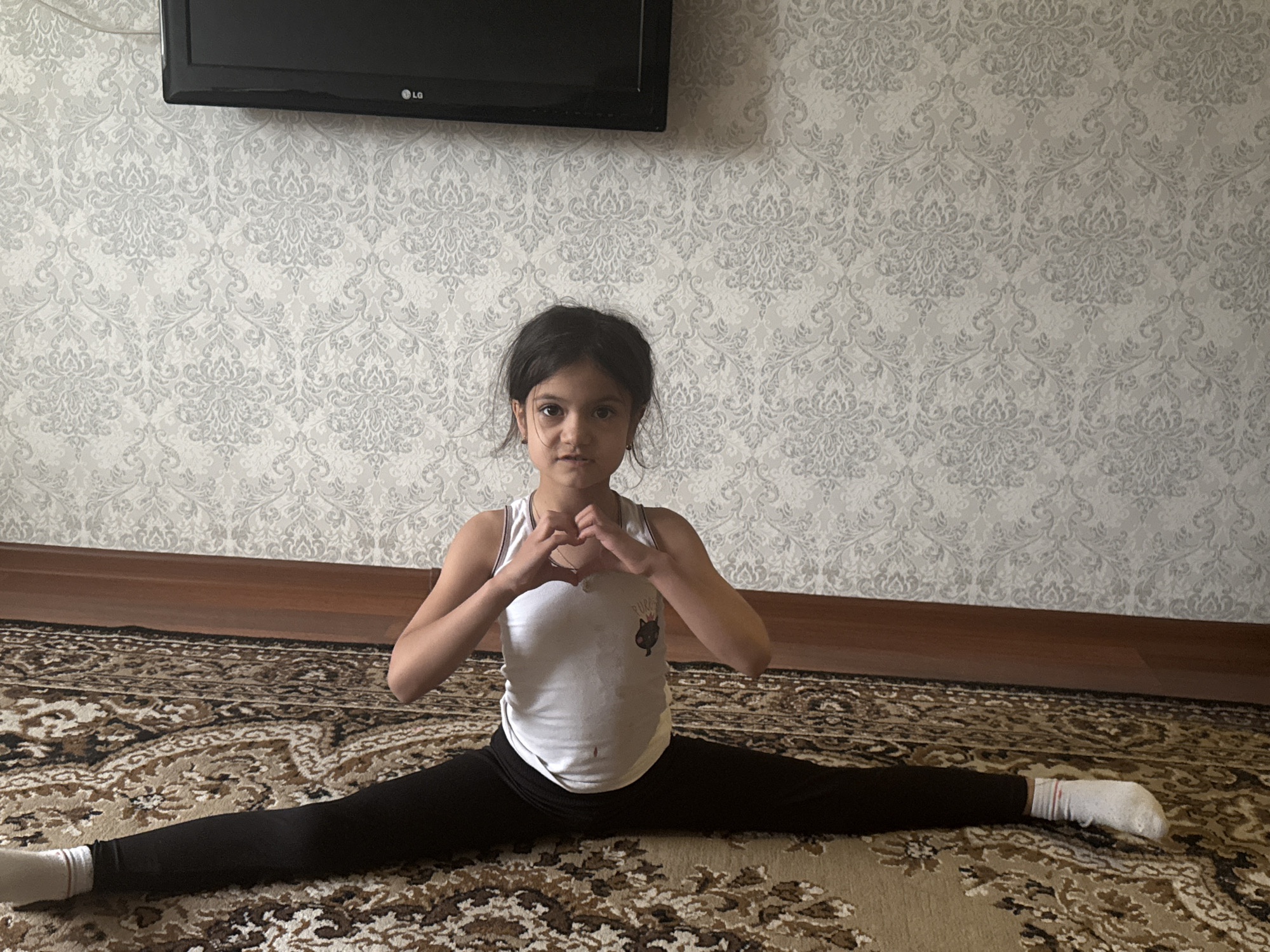 Child practices gymnastics routine indoors during overcast afternoon
