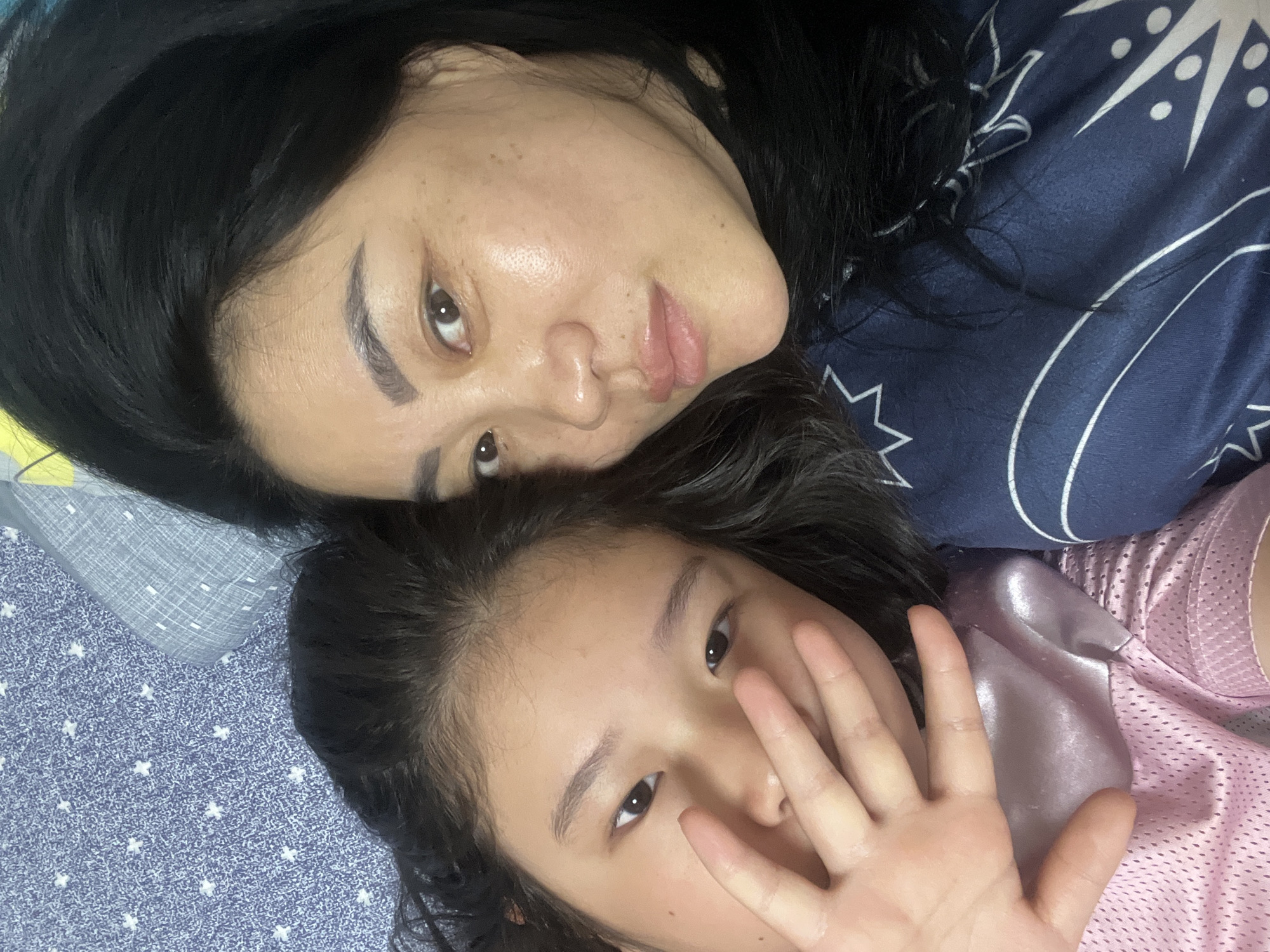 Woman and girl share playful moment on patterned bed
