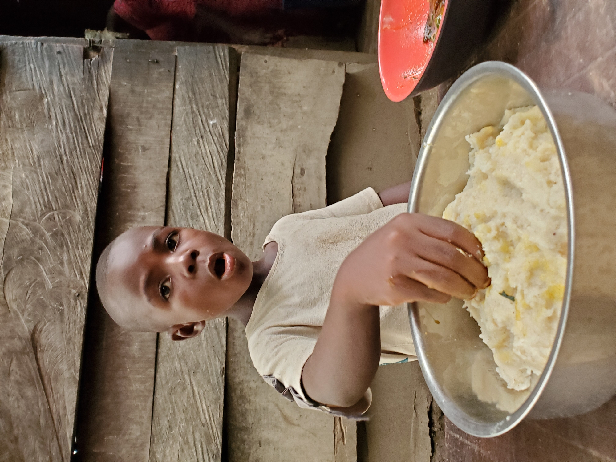 Child reaches for fufu in rustic Nigerian home