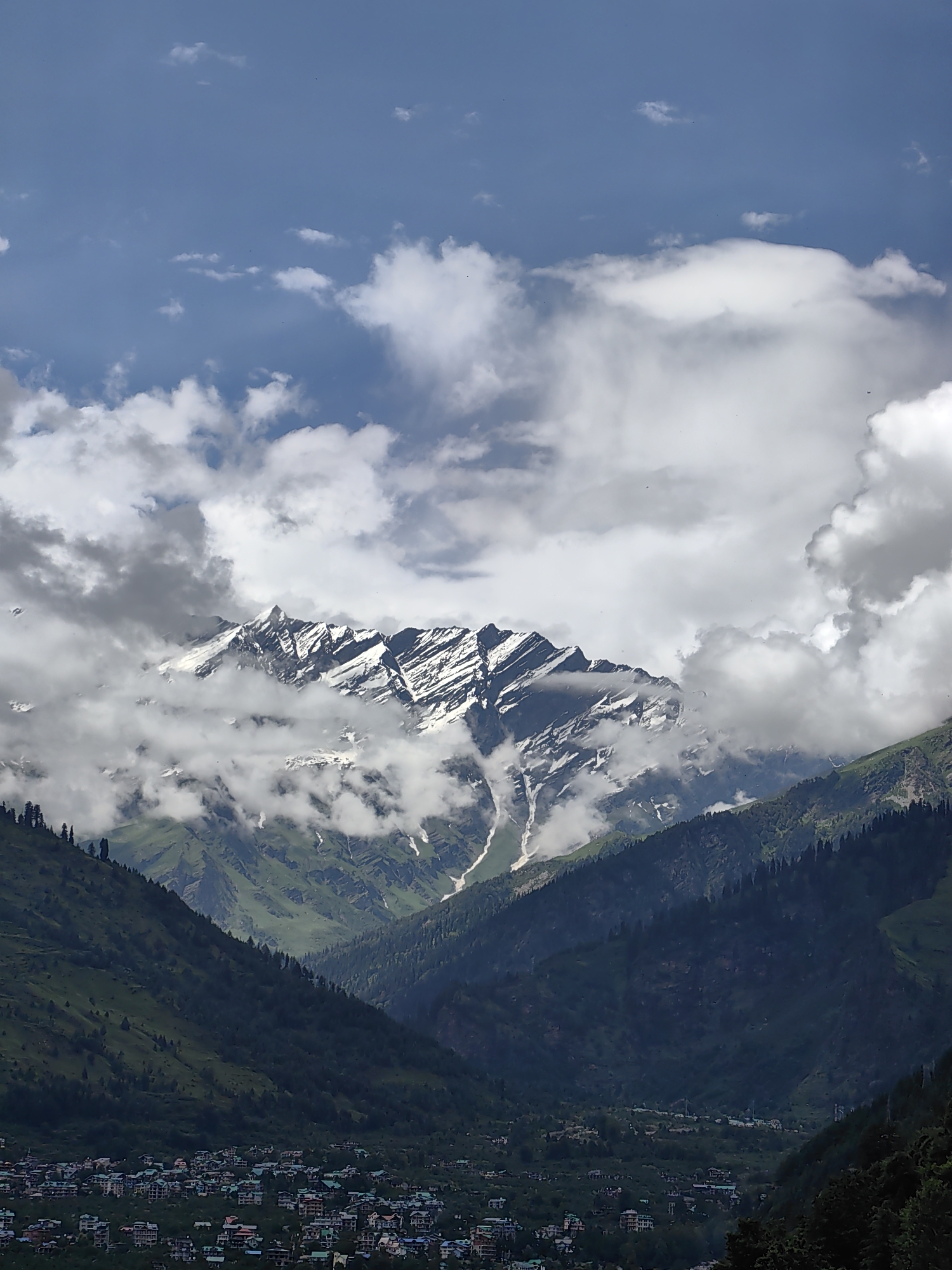 Vashisht valley and Himalayan peaks under a cloudy summer sky