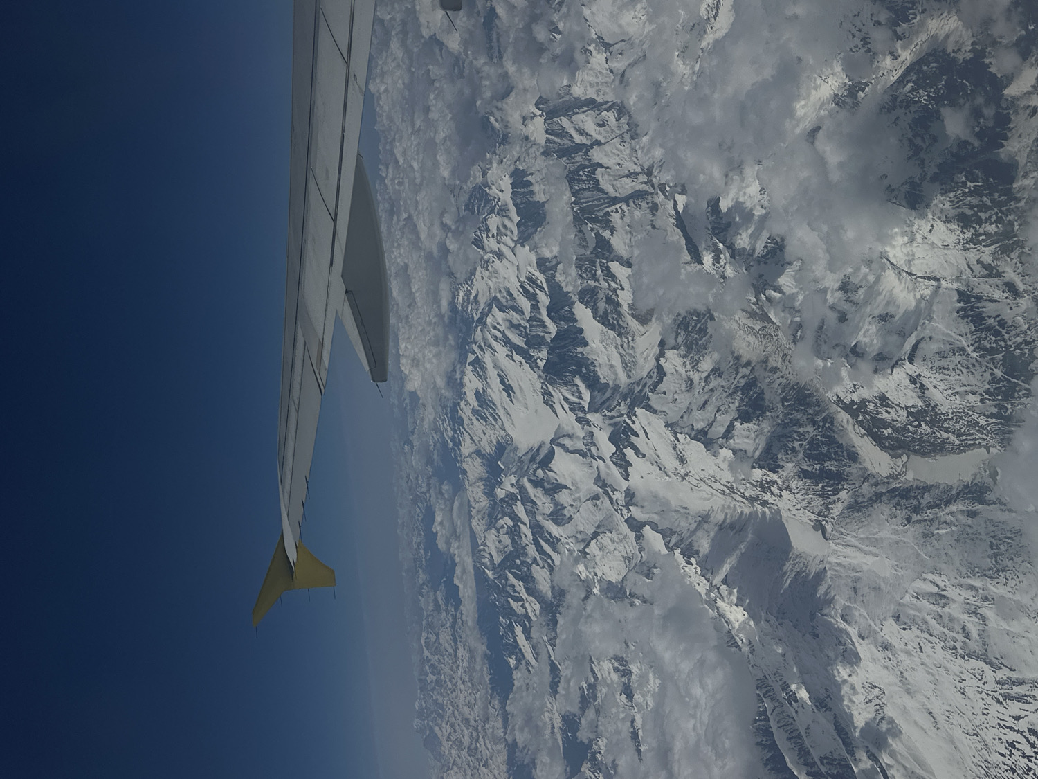 Aerial view captures aircraft wing over snowy mountains near London