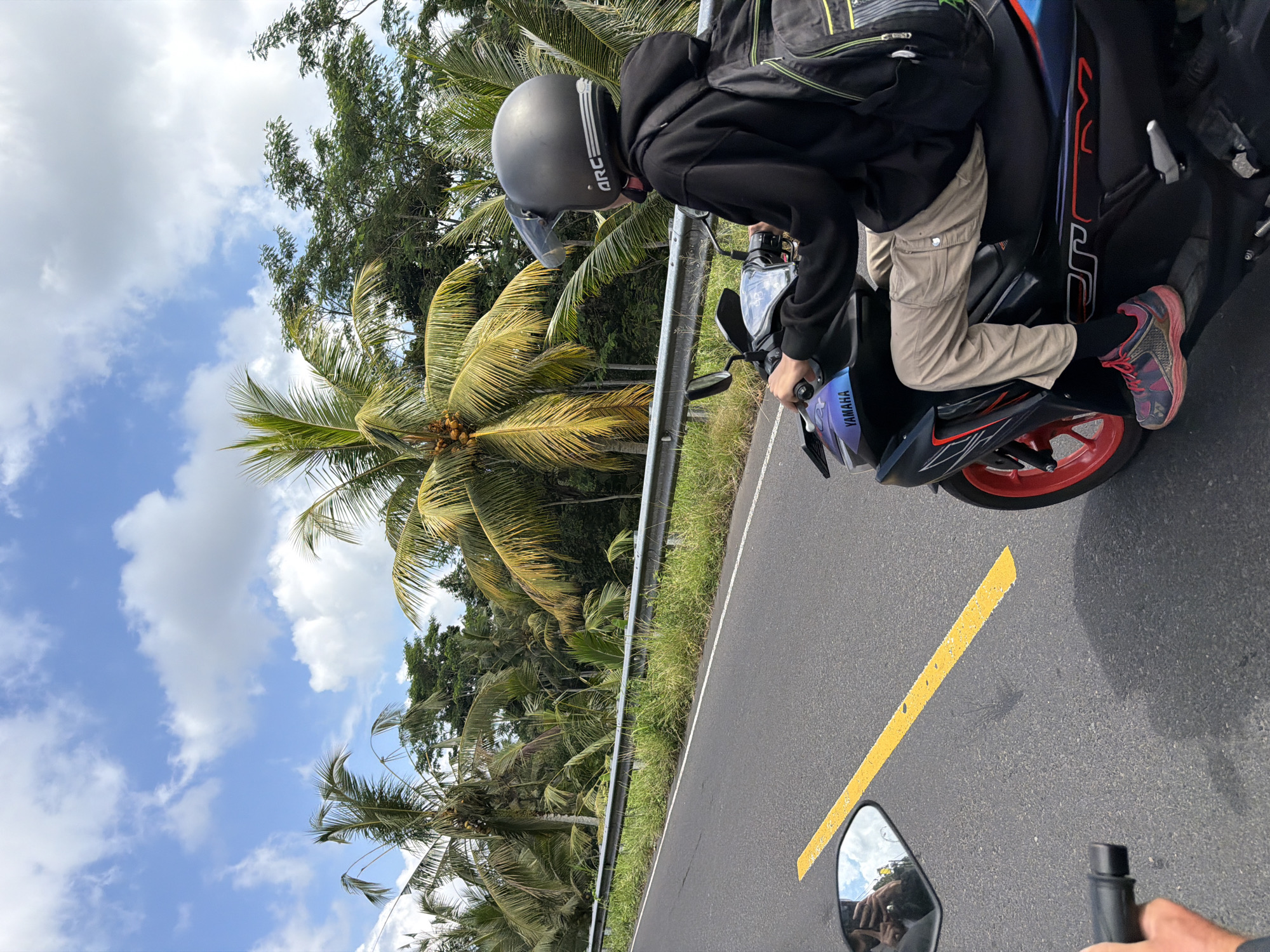 Motorcycle traffic through a lush Tampaksiring road on a cloudy morning