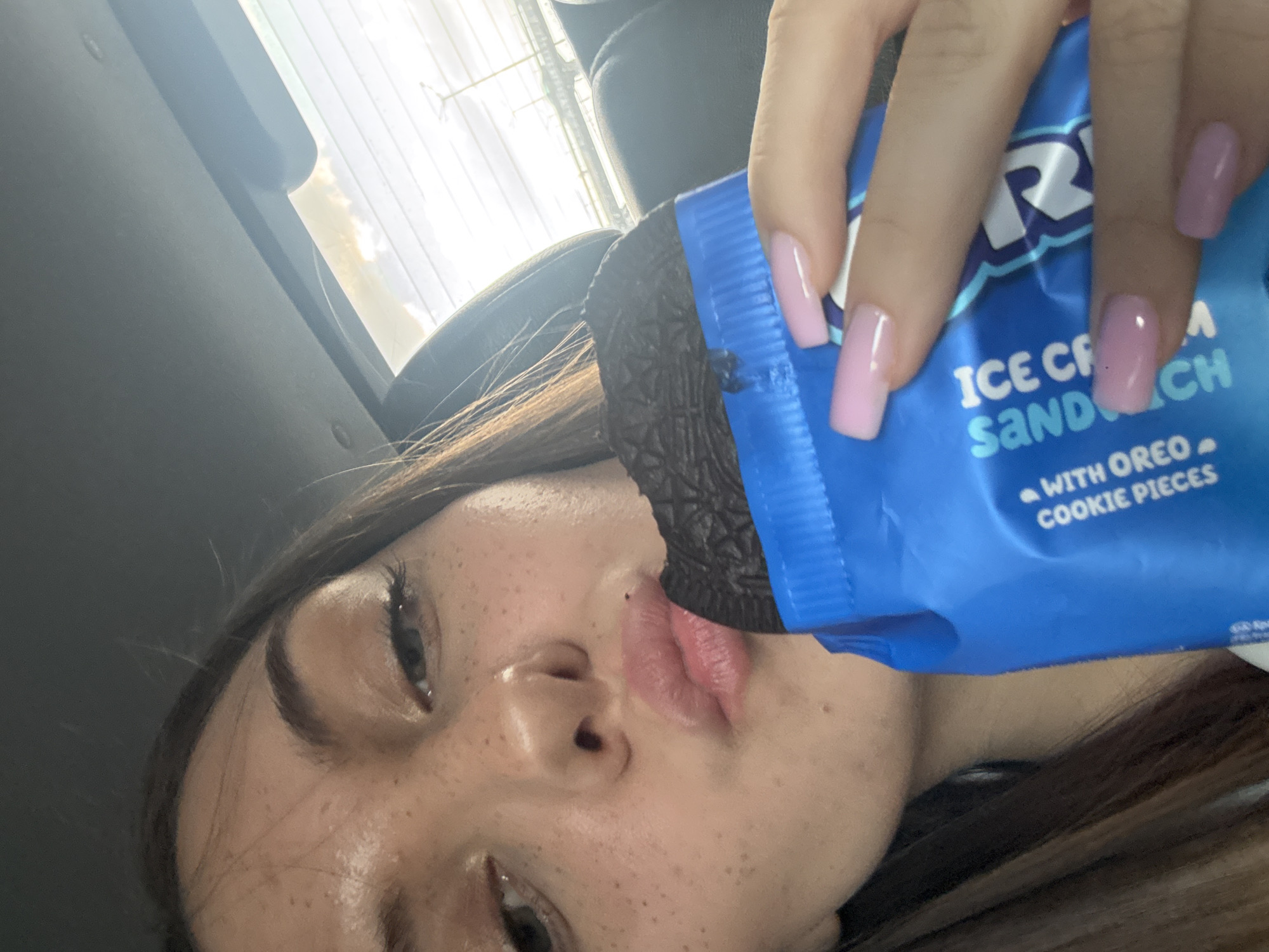 Person enjoys Oreo ice cream sandwich in car, Sofia