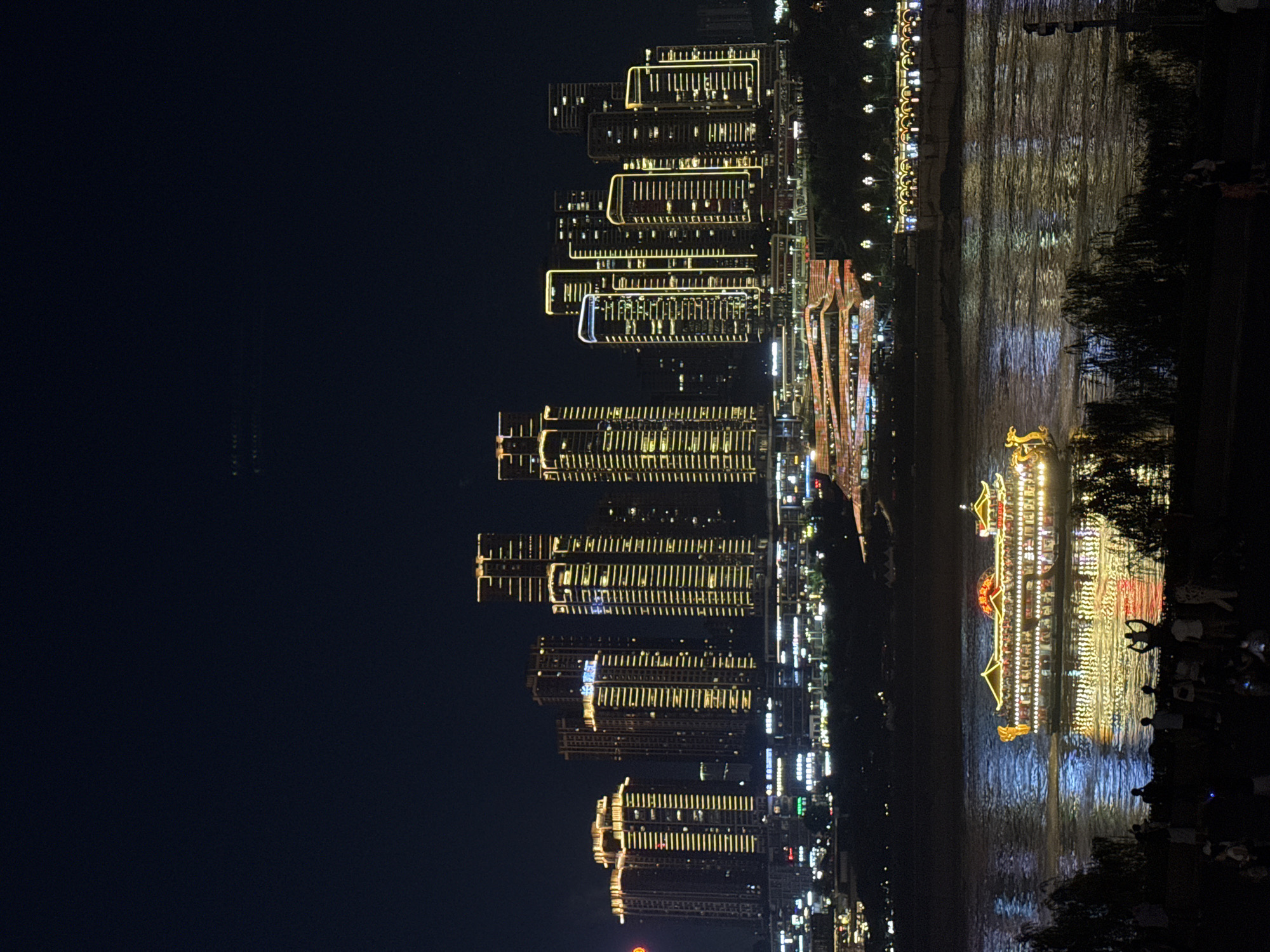 Illuminated boats cruise Chongqing's Jialing River amid glowing cityscape