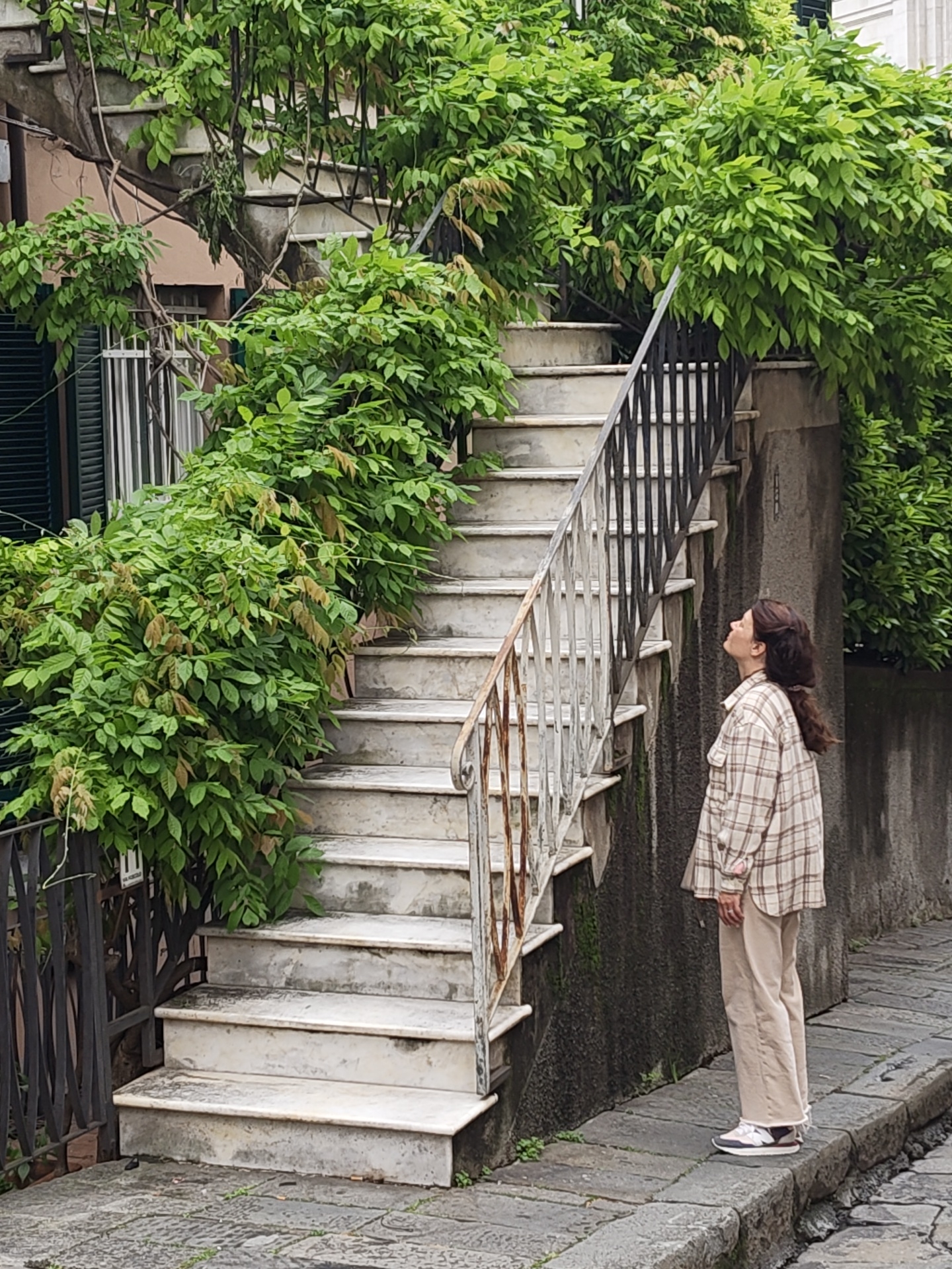 Woman observed on cobblestone street in historic Genoa