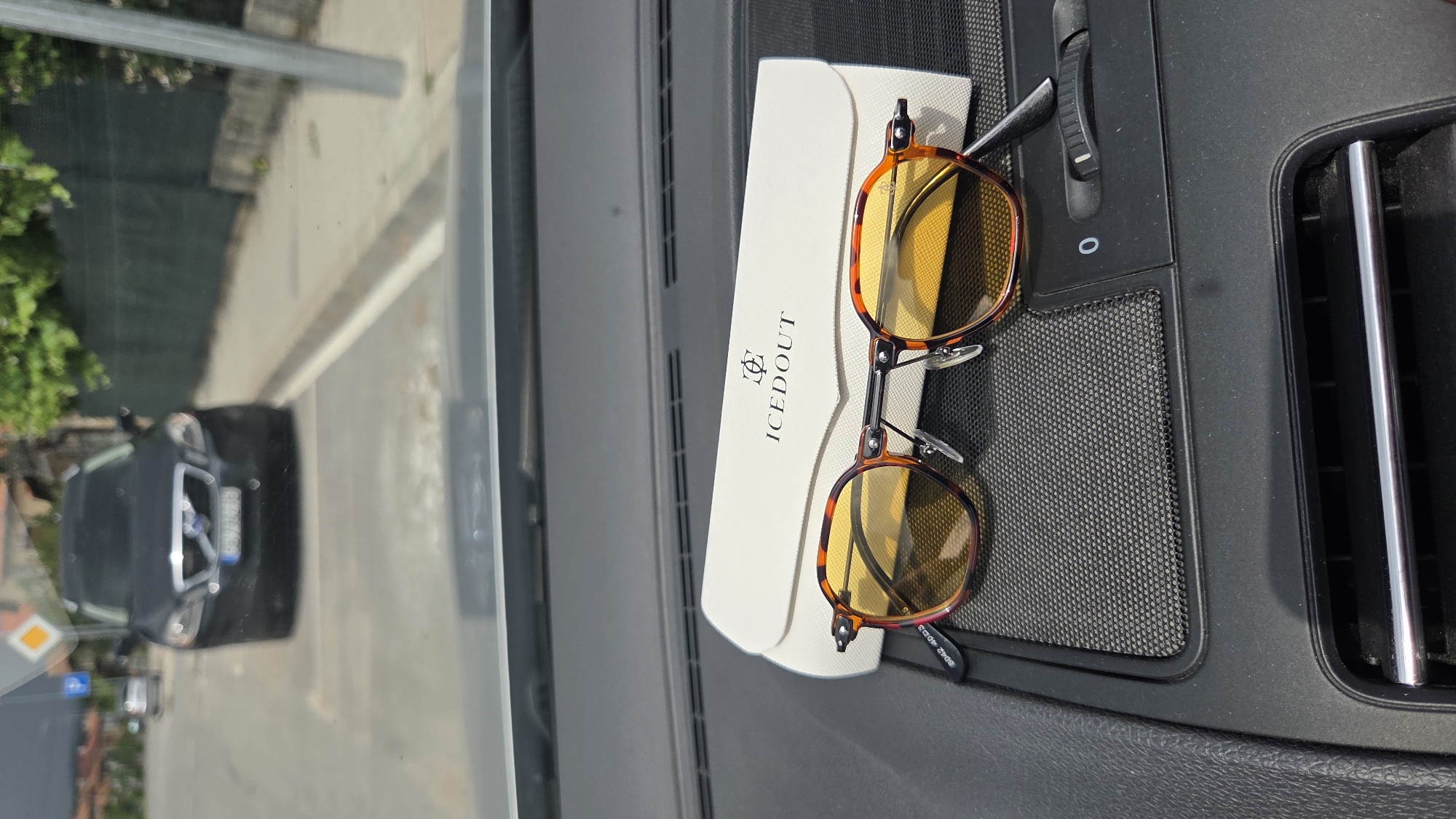 Tortoise-shell sunglasses and case on a car dashboard