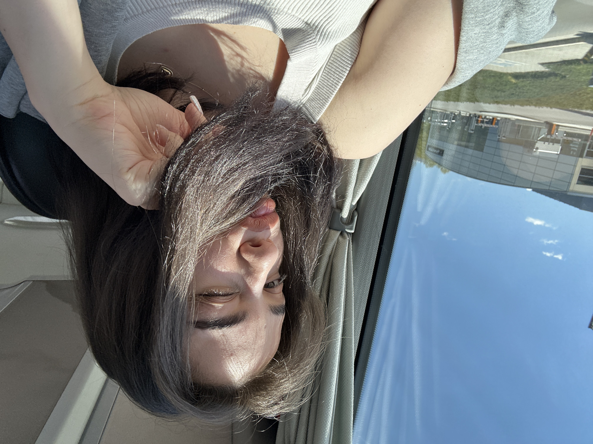 Woman winks while holding hair inside vehicle in Pancharevo