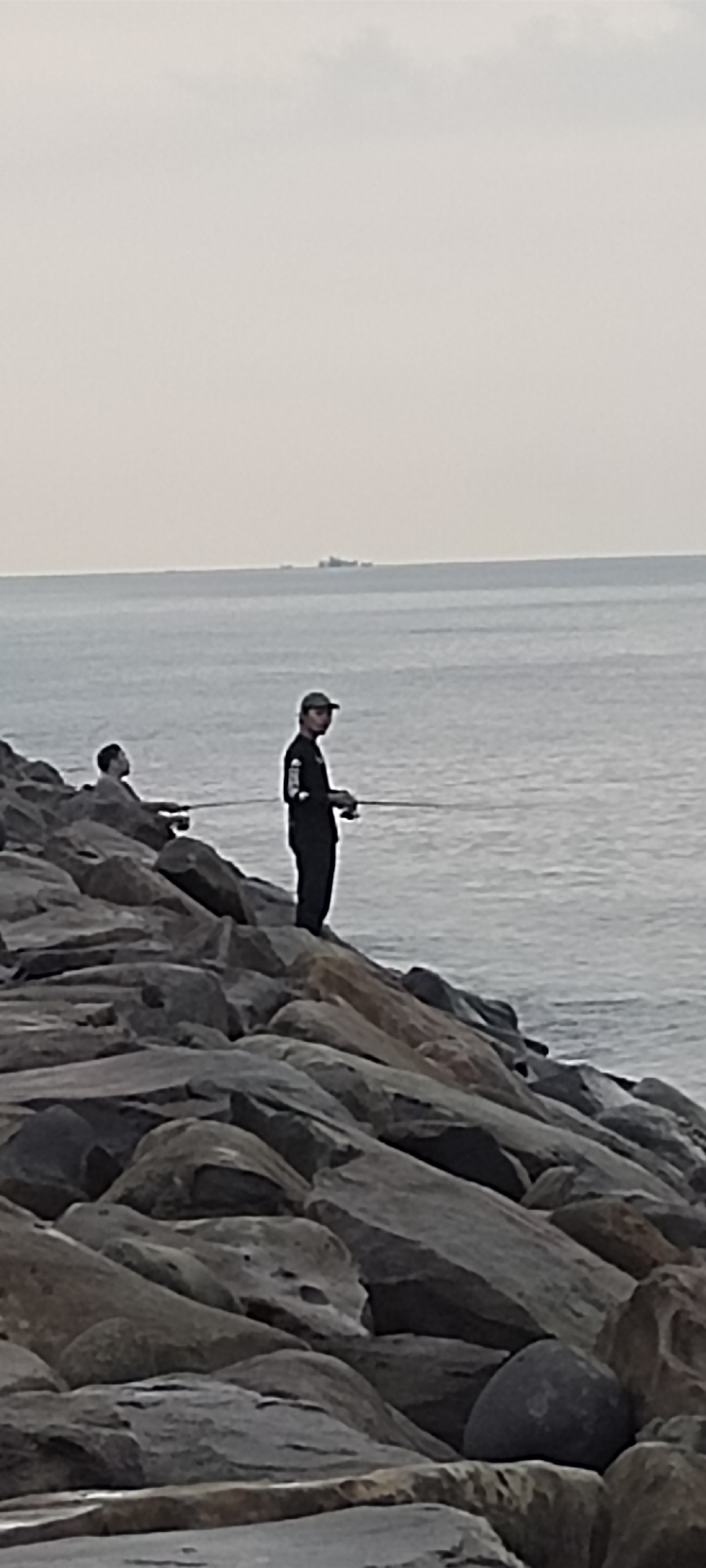 Fishing and coastal life along Lhokseumawe's rocky shoreline