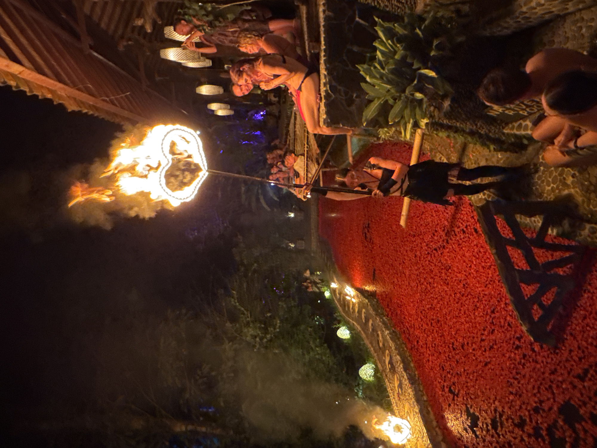 Nighttime fire spinning performance at an outdoor venue in Blahbatuh