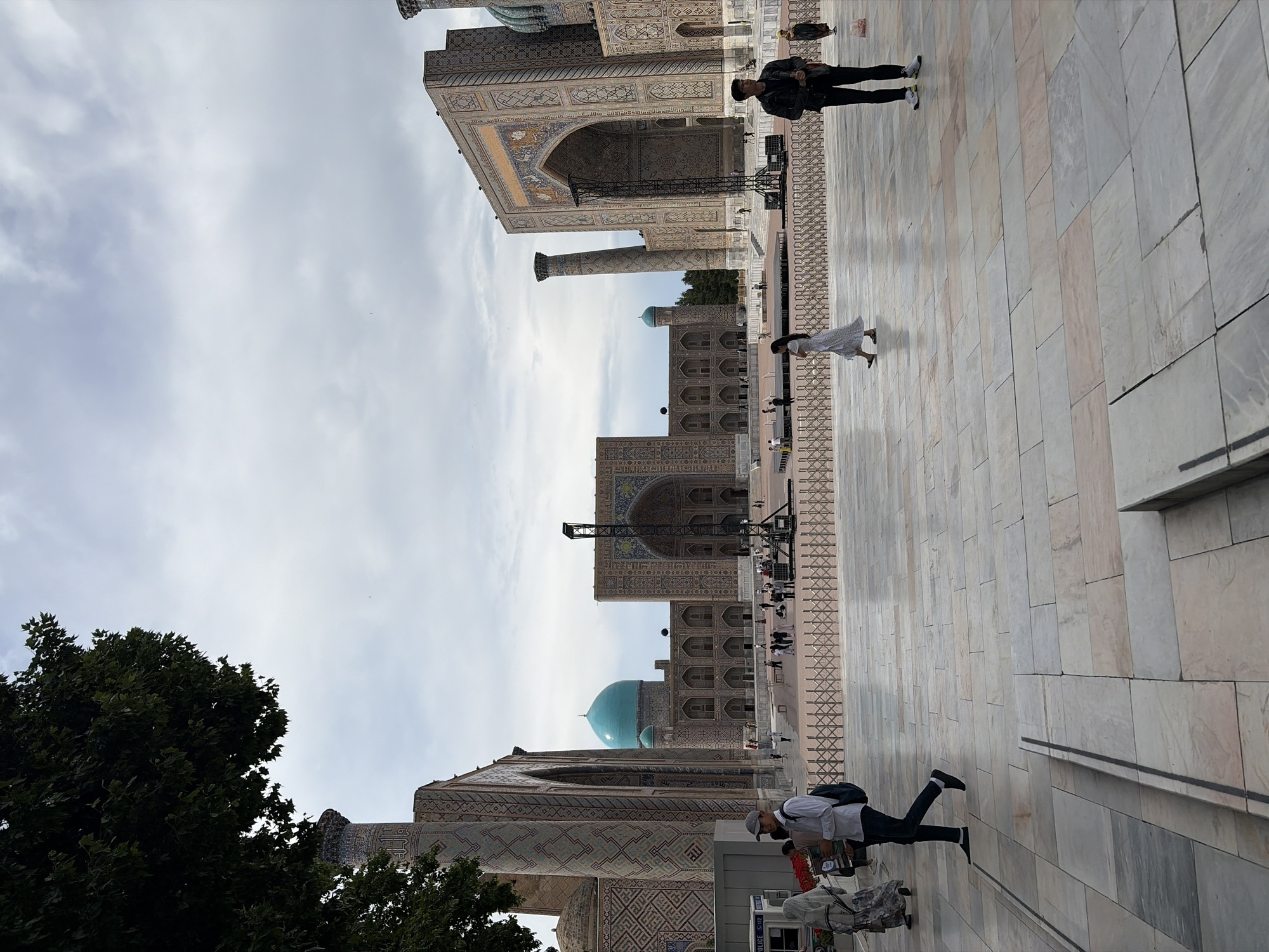 Tourist documents Samarkand's Registan Square architectural complex under overcast skies