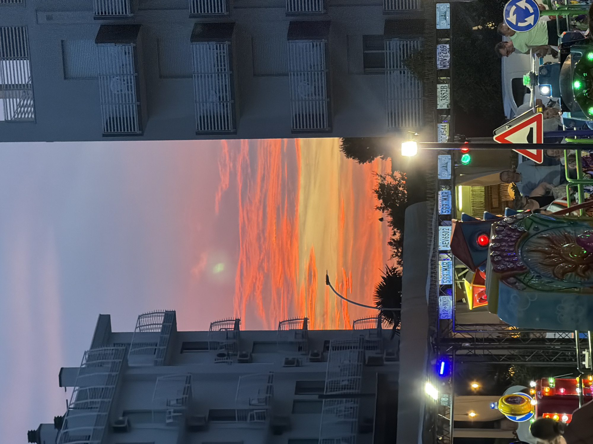Sunset over a Jesolo amusement park flanked by apartment buildings