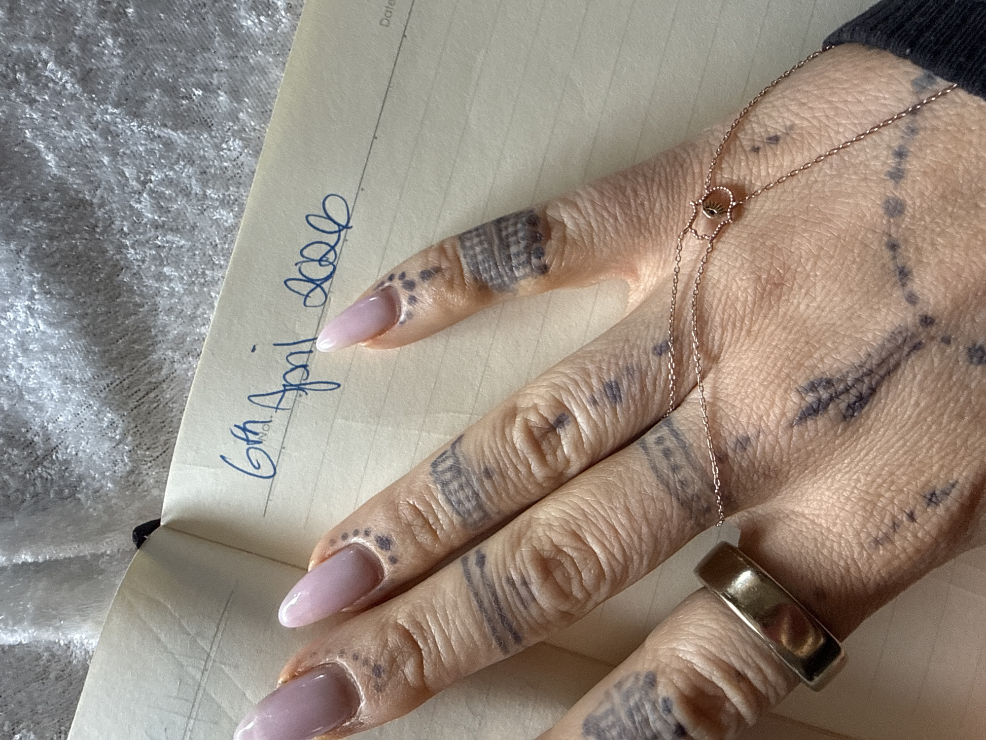 Tattooed hand photographed resting on notebook in Strömstad