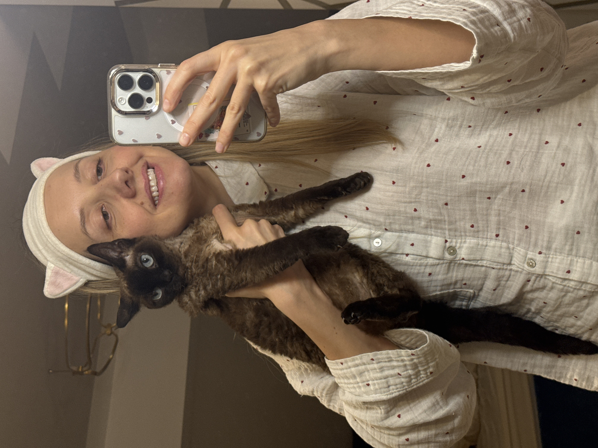 Woman takes selfies with cat wearing matching cat ears