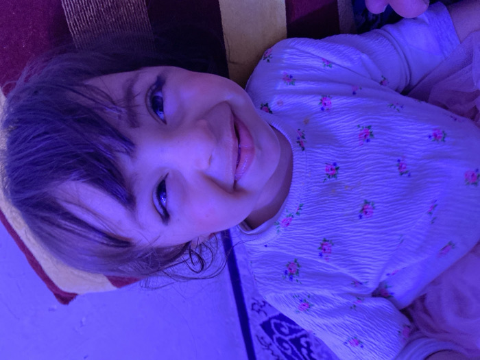 Child photographed indoors under purple lighting in Kandahar