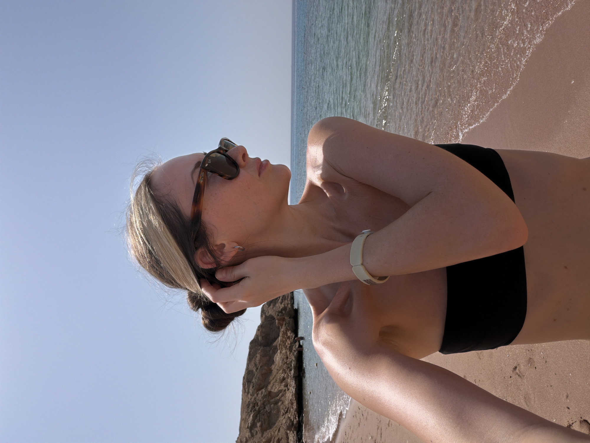 Woman enjoys morning sunbath on unidentified beach