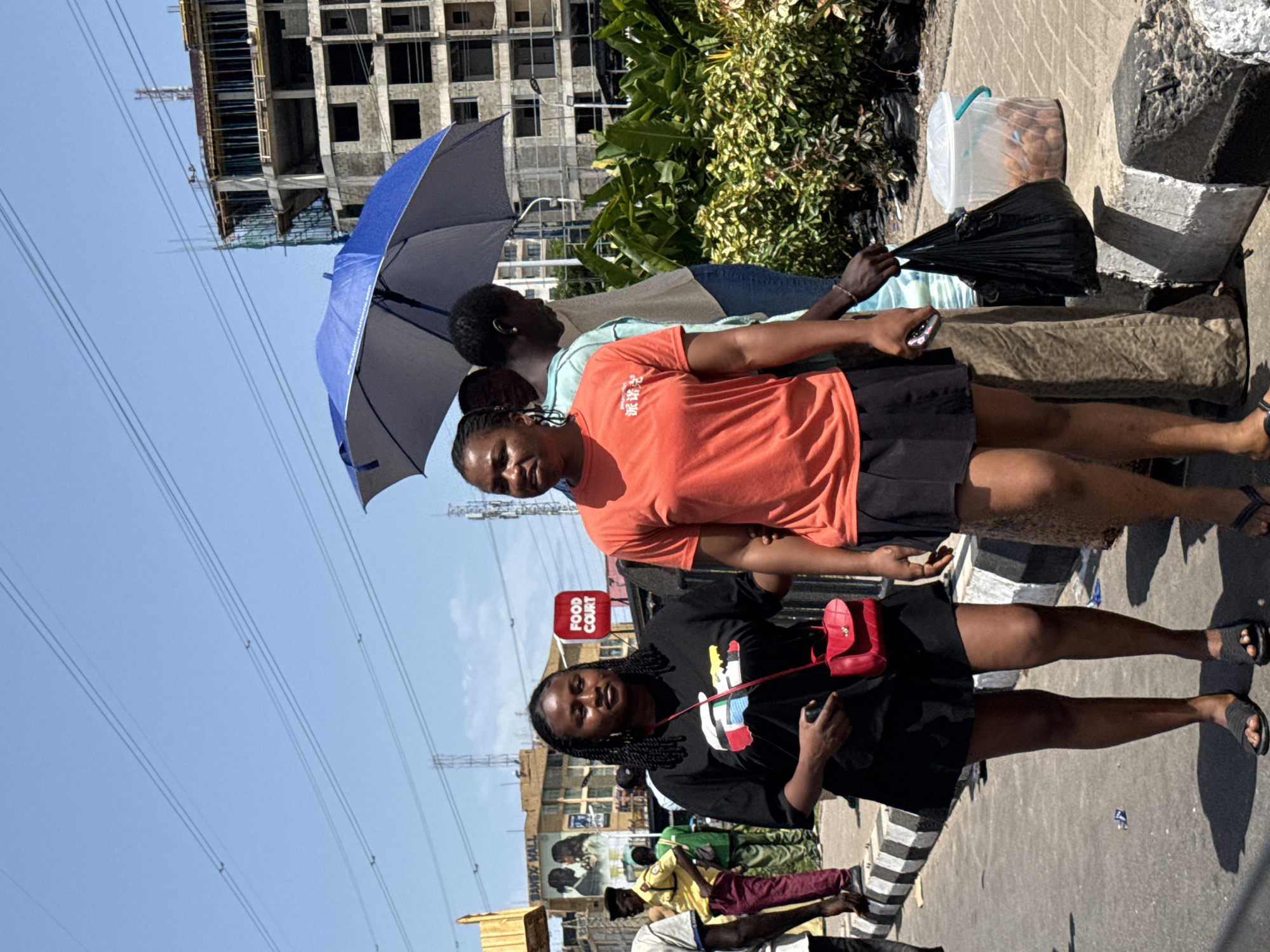 Four people gather on sidewalk in Ilado, Nigeria