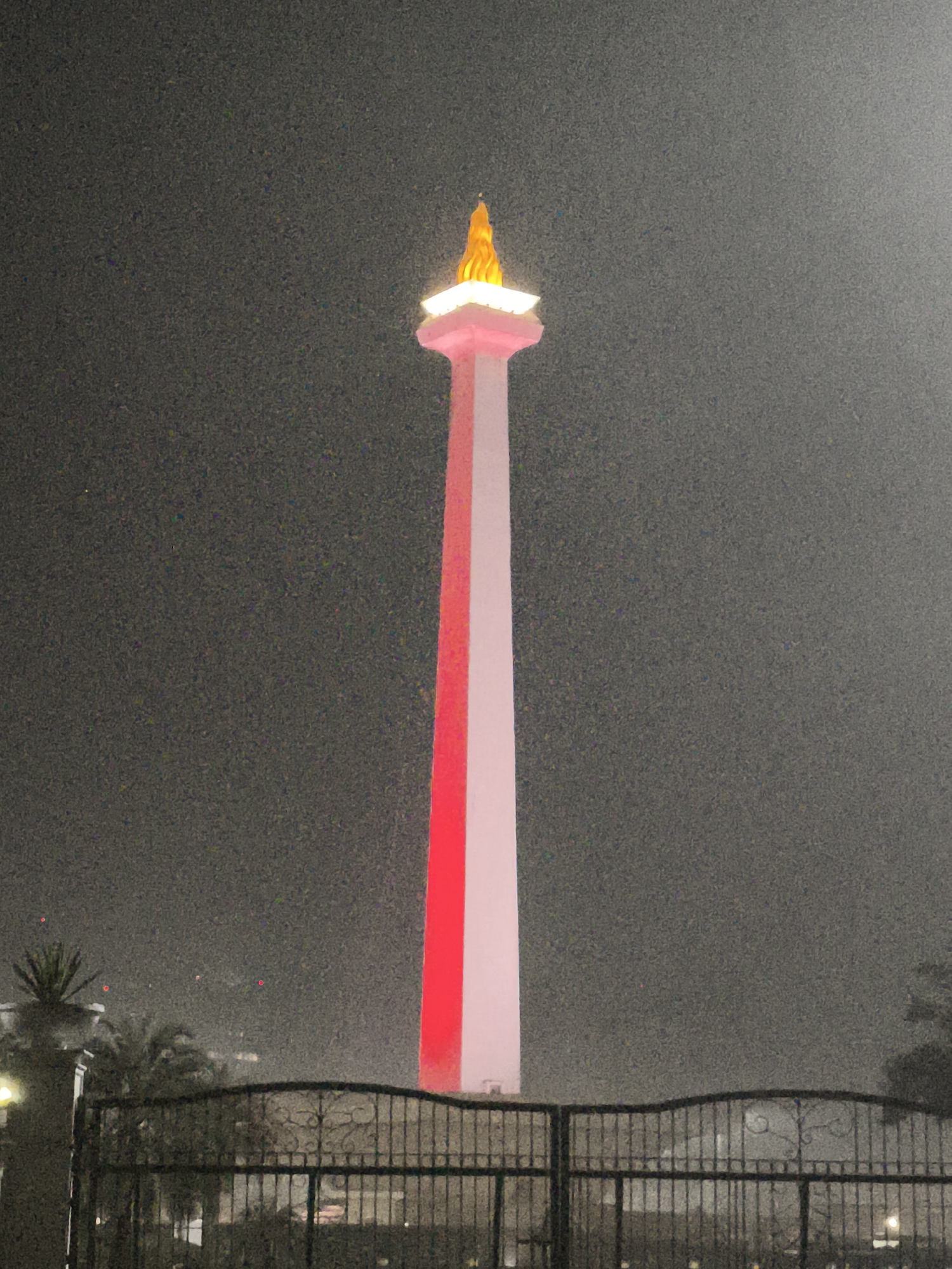 Monas tower illuminated through misty night in Jakarta