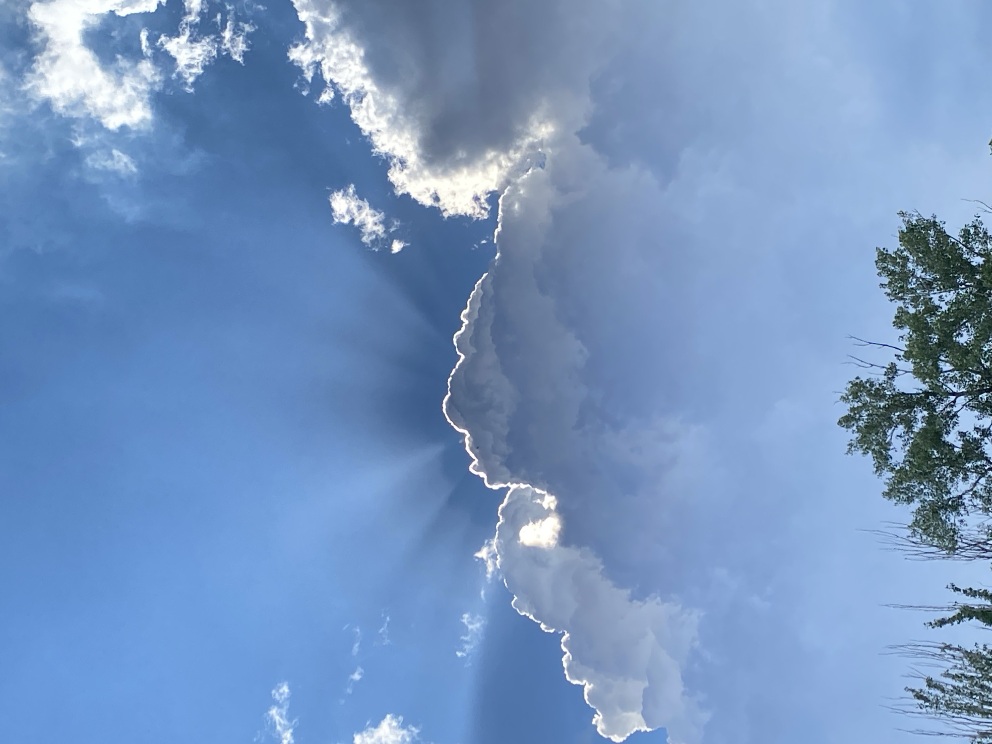 Dramatic sunbeams burst through clouds in afternoon sky