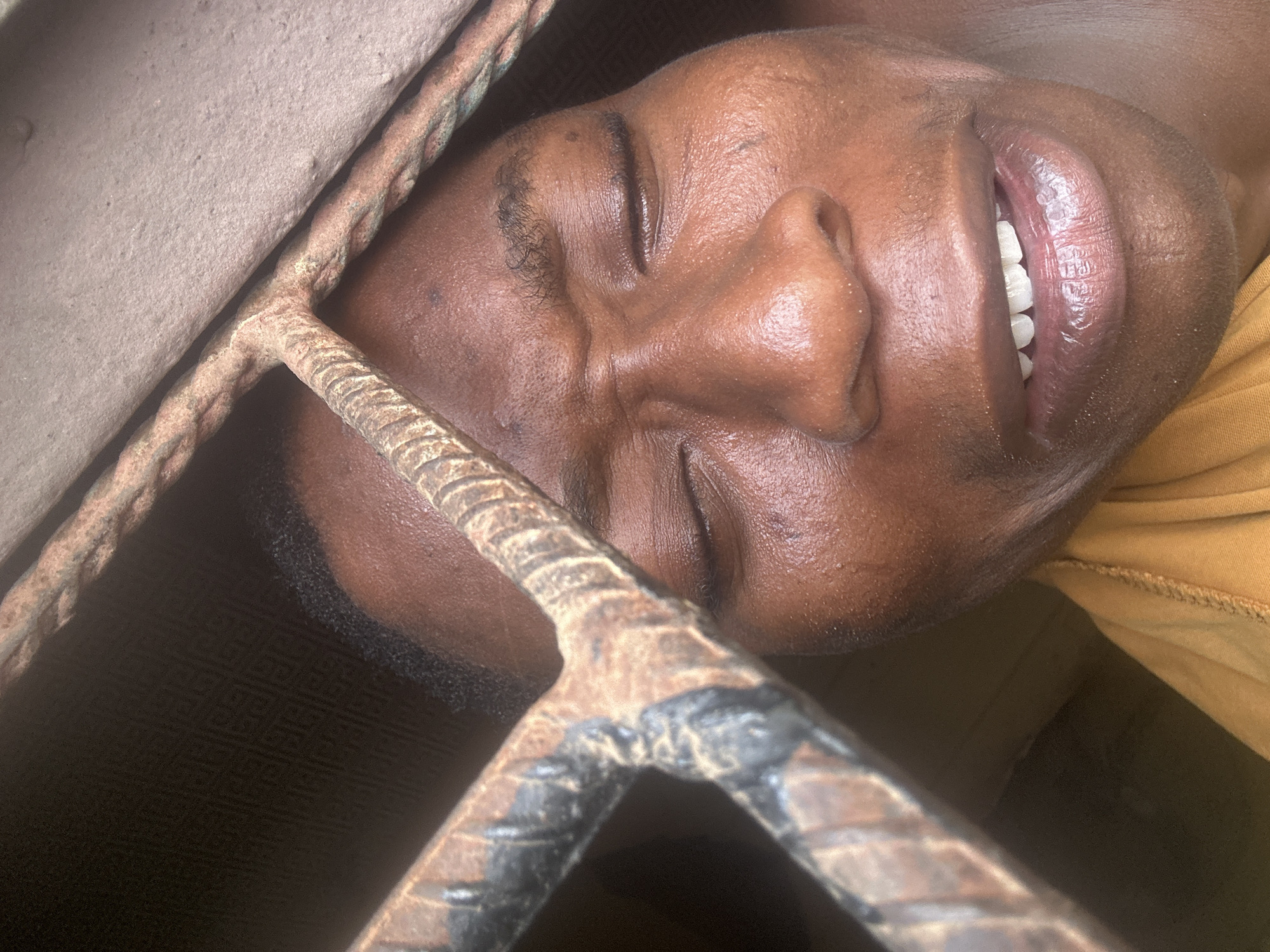 Person photographed making various expressions near metal bars