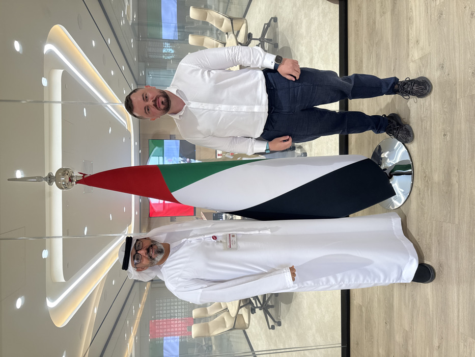 Men pose with UAE flag near Dubai Knowledge College
