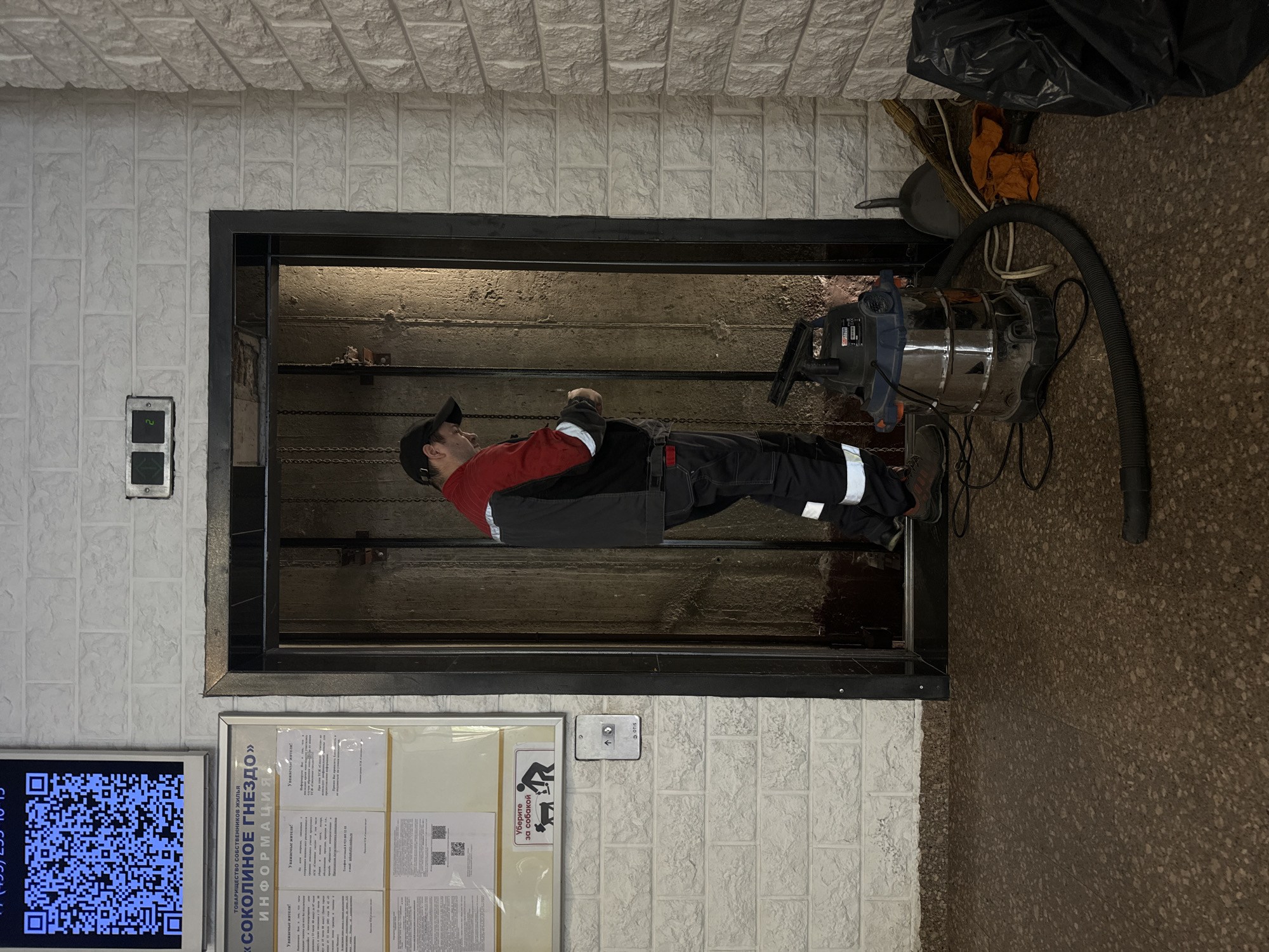 Maintenance worker performs repairs in open elevator shaft