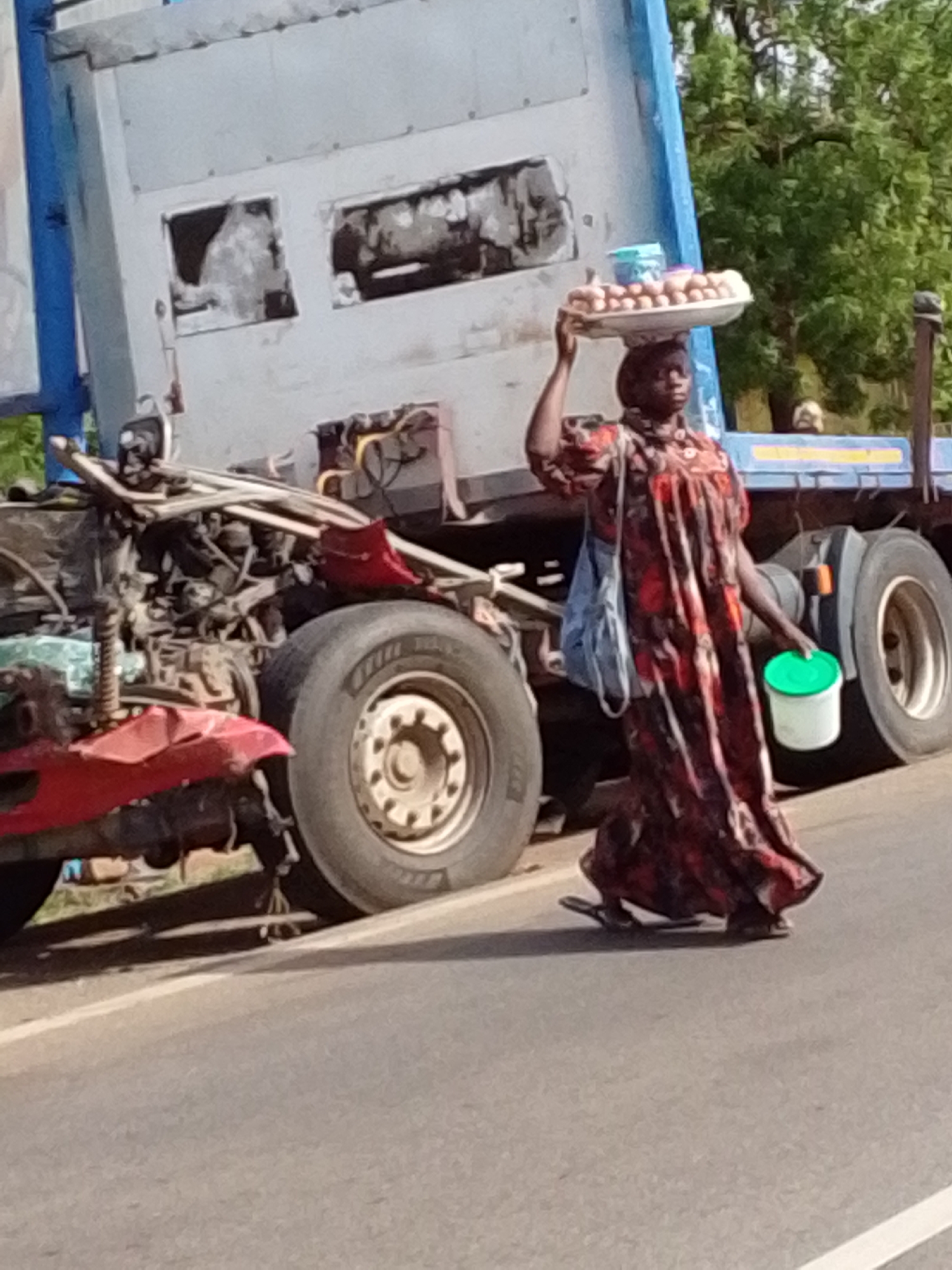 Woman carries food through traffic jam in Dungu, Ghana