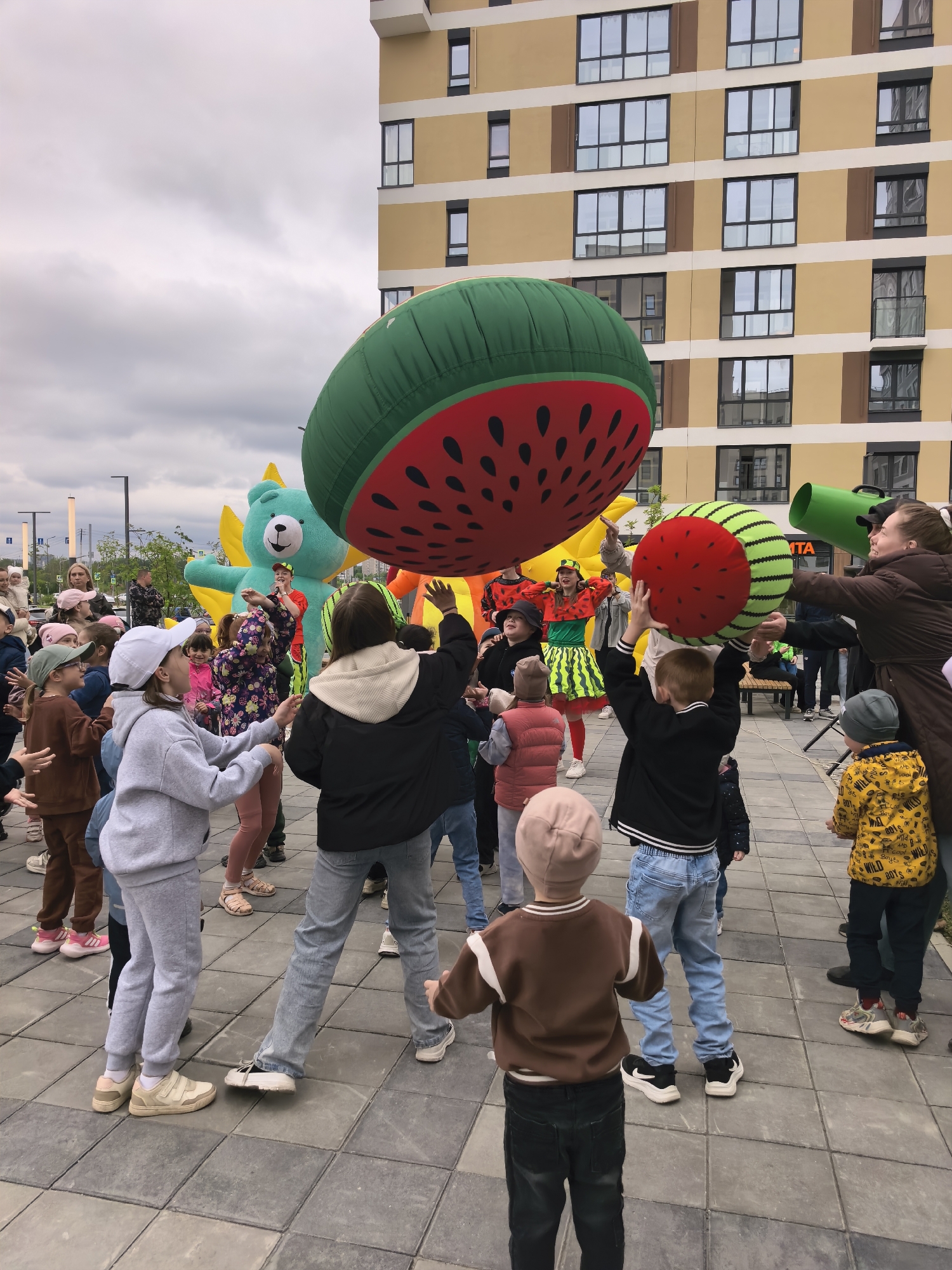 Children's foam party features watermelon-costumed performers in urban courtyard