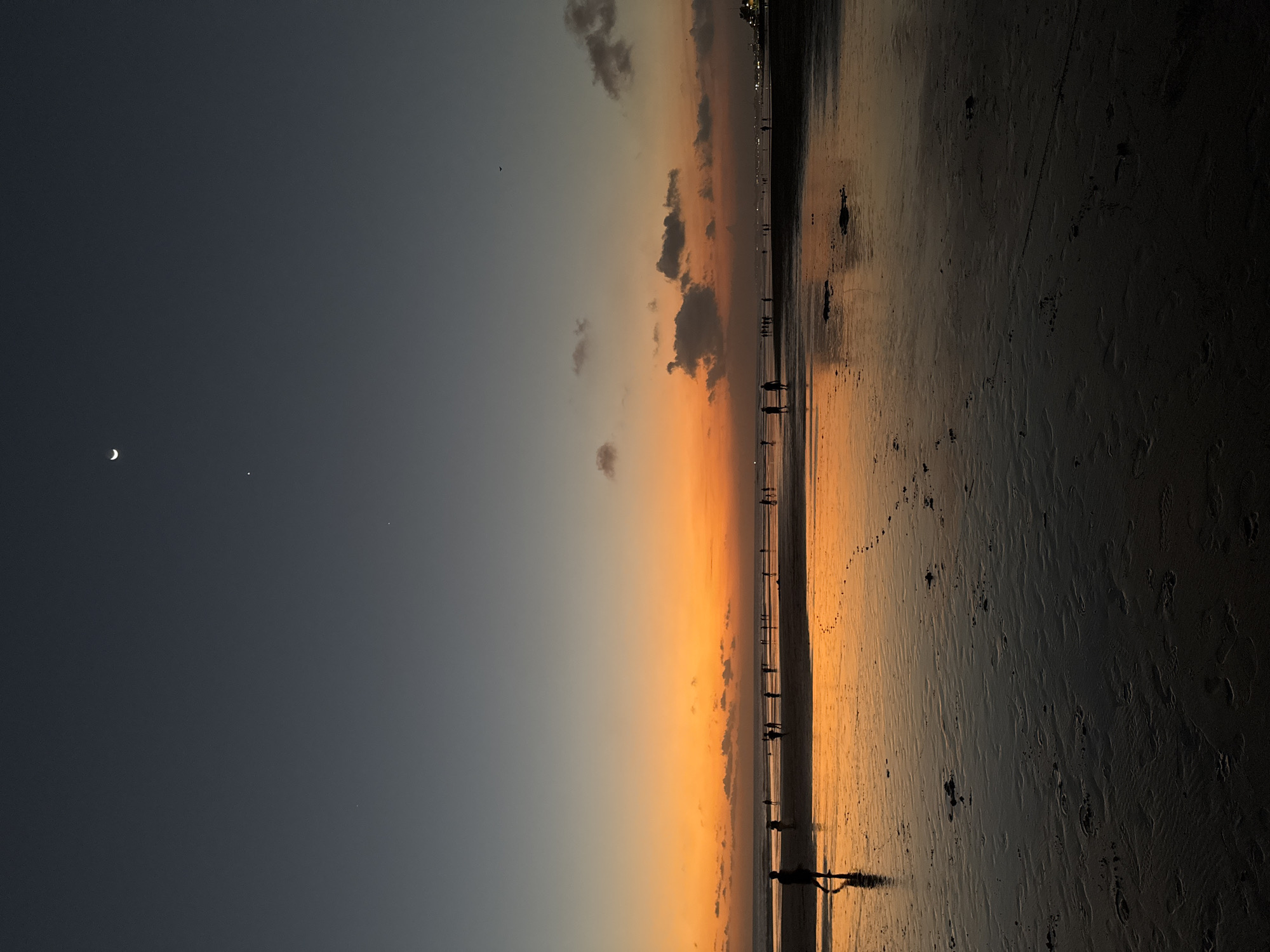 Sunset soccer and strollers on Kuta Beach's reflective shoreline