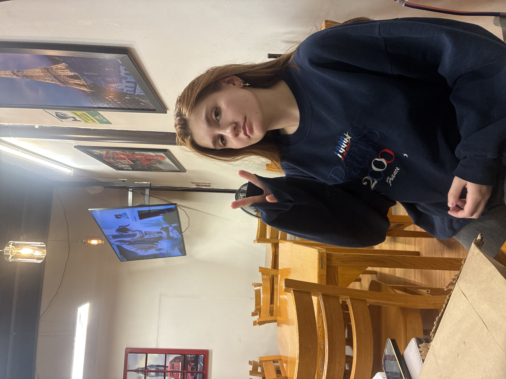 Woman in Paris 2024 sweatshirt poses at Mexican restaurant