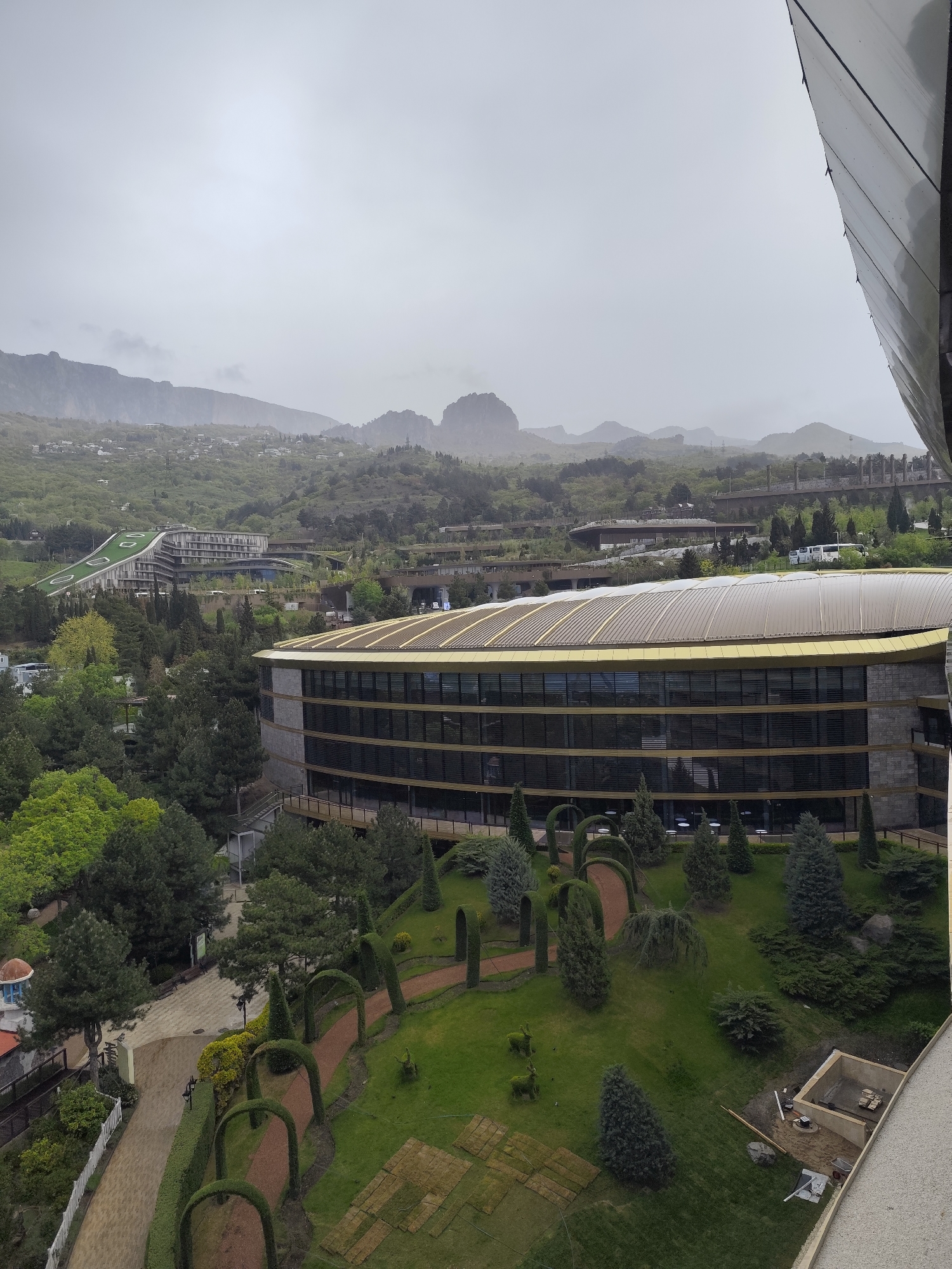 High-angle view captures modern complex amid mountains, cloudy skies