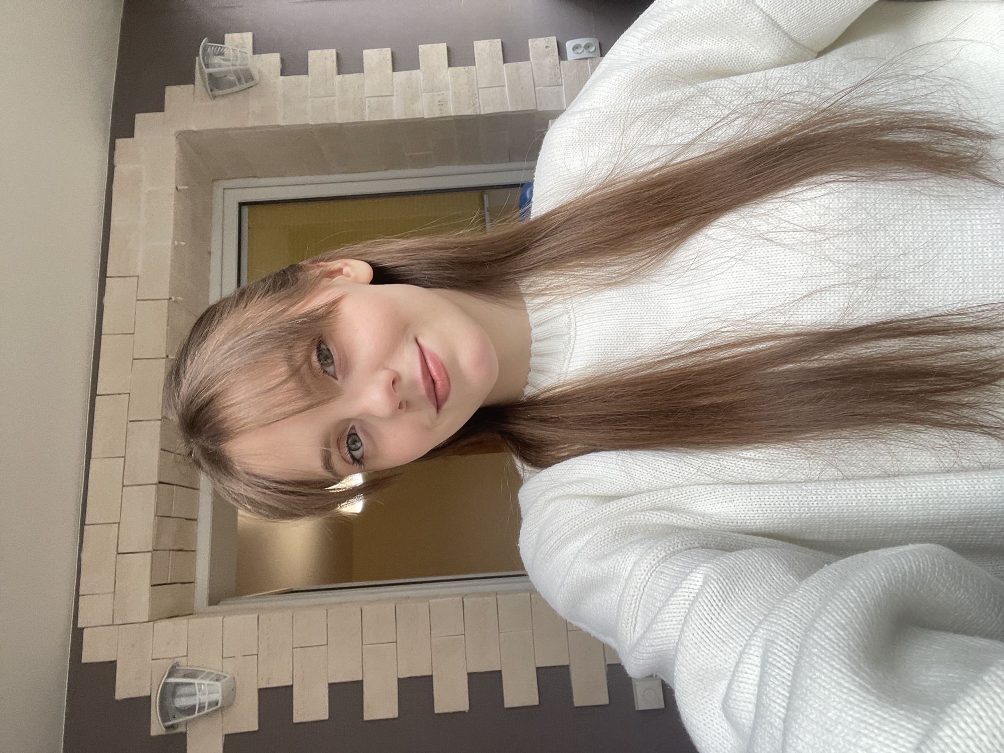 Woman takes morning selfies by window in Ufa