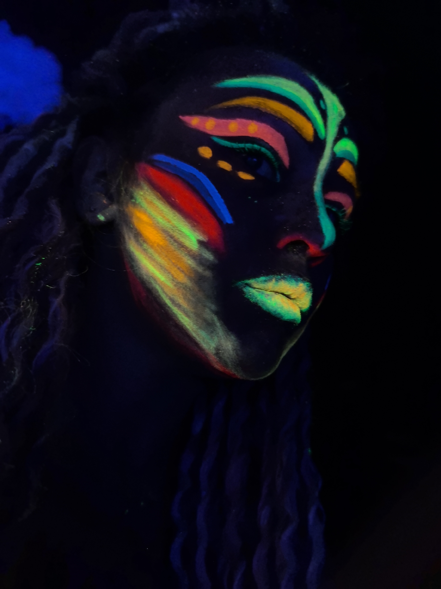 Person applies elaborate neon face paint under blacklight in Russia