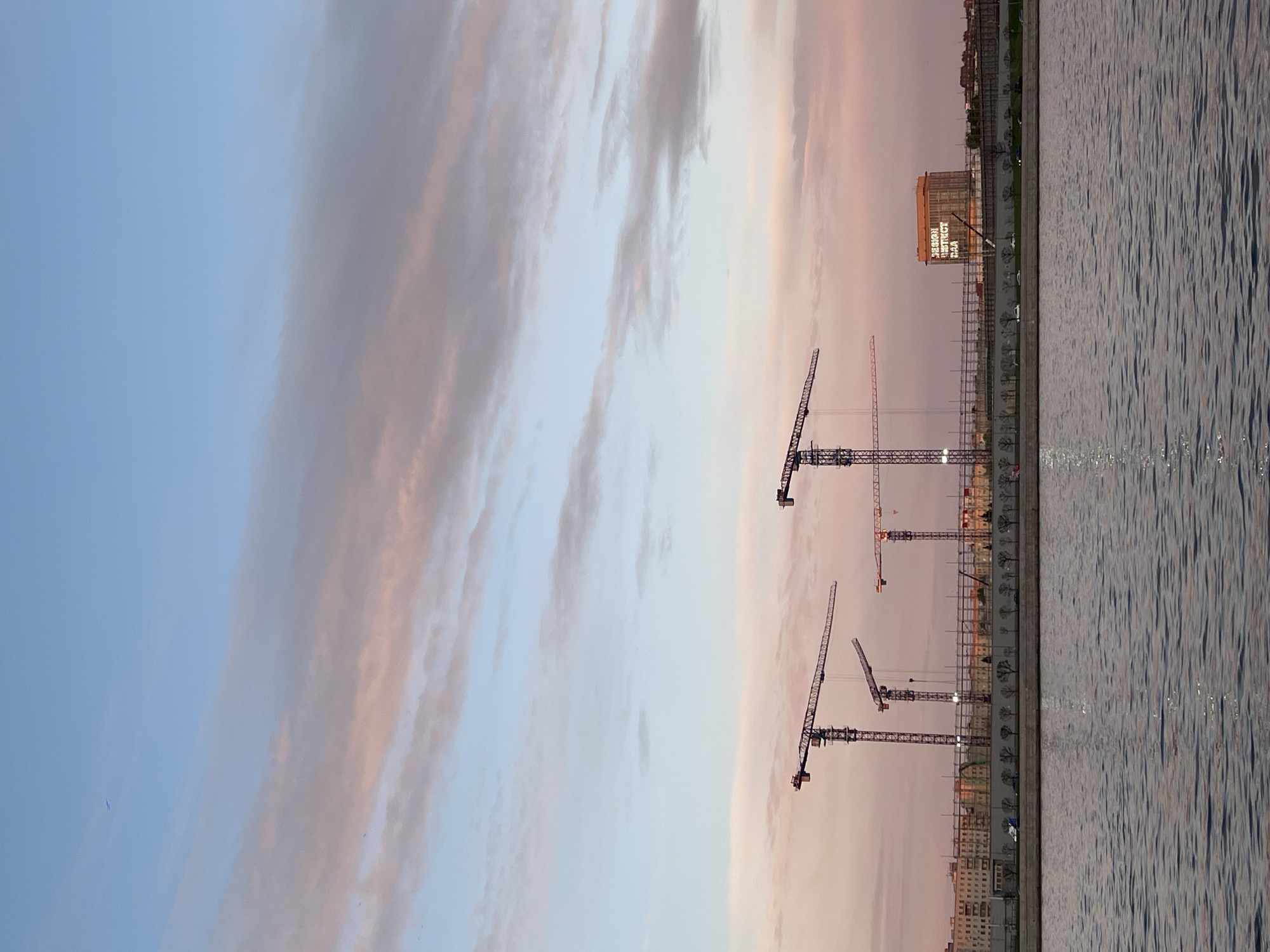 Dusk waterfront scene captured in Saint Petersburg with construction cranes