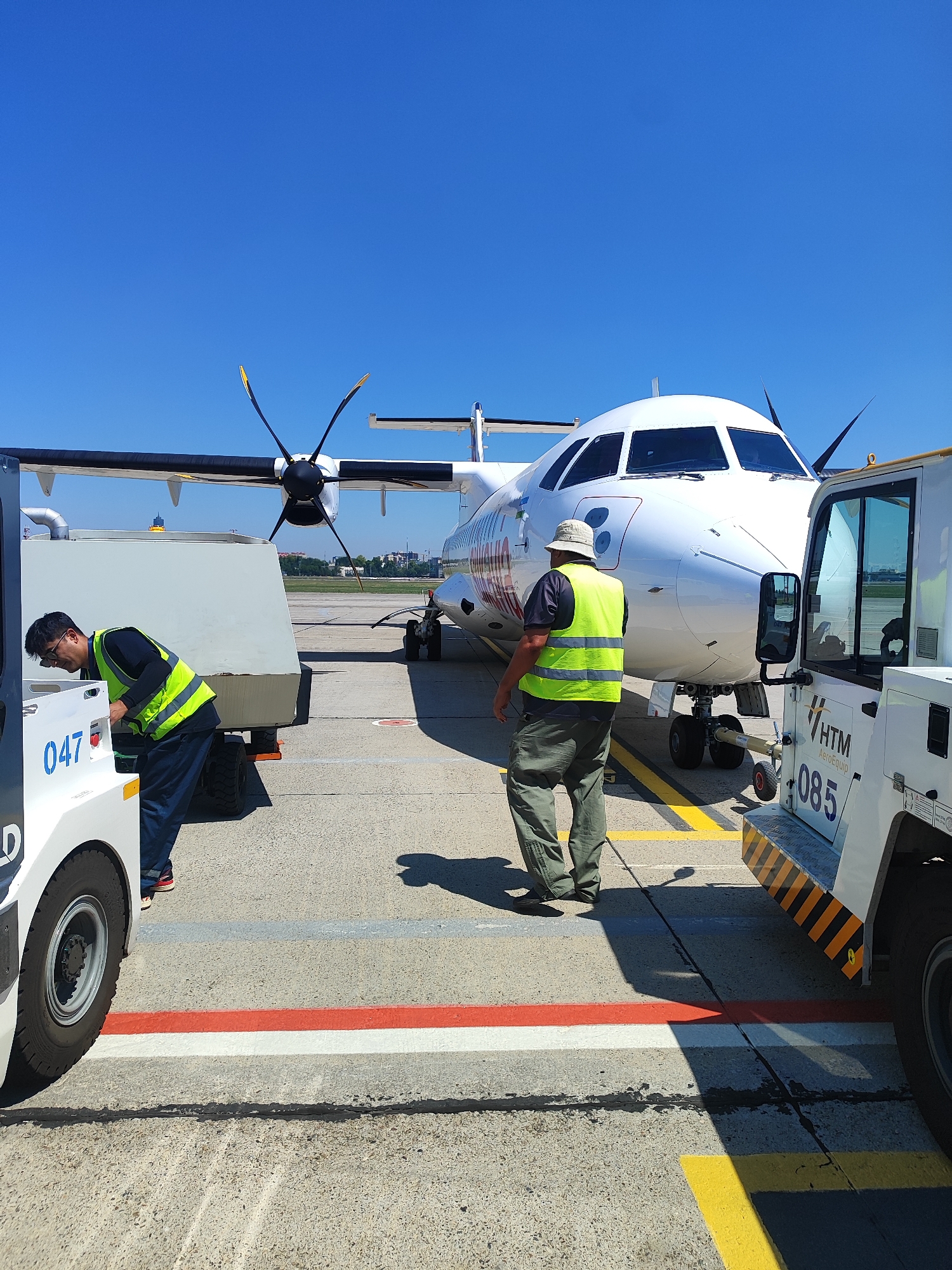 Silkway propeller aircraft on tarmac with ground crew activity