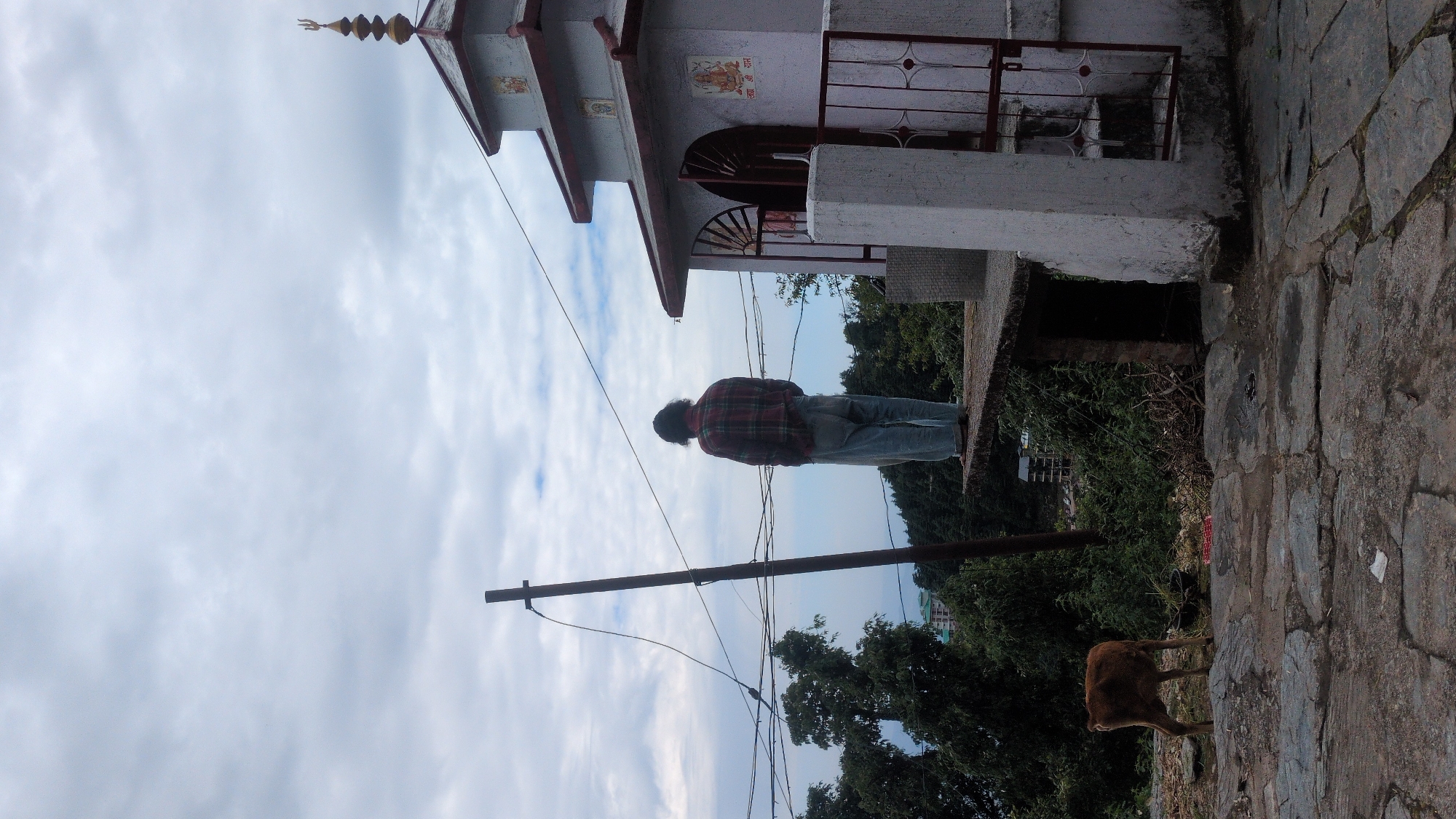Person visits small temple in Haini during overcast morning