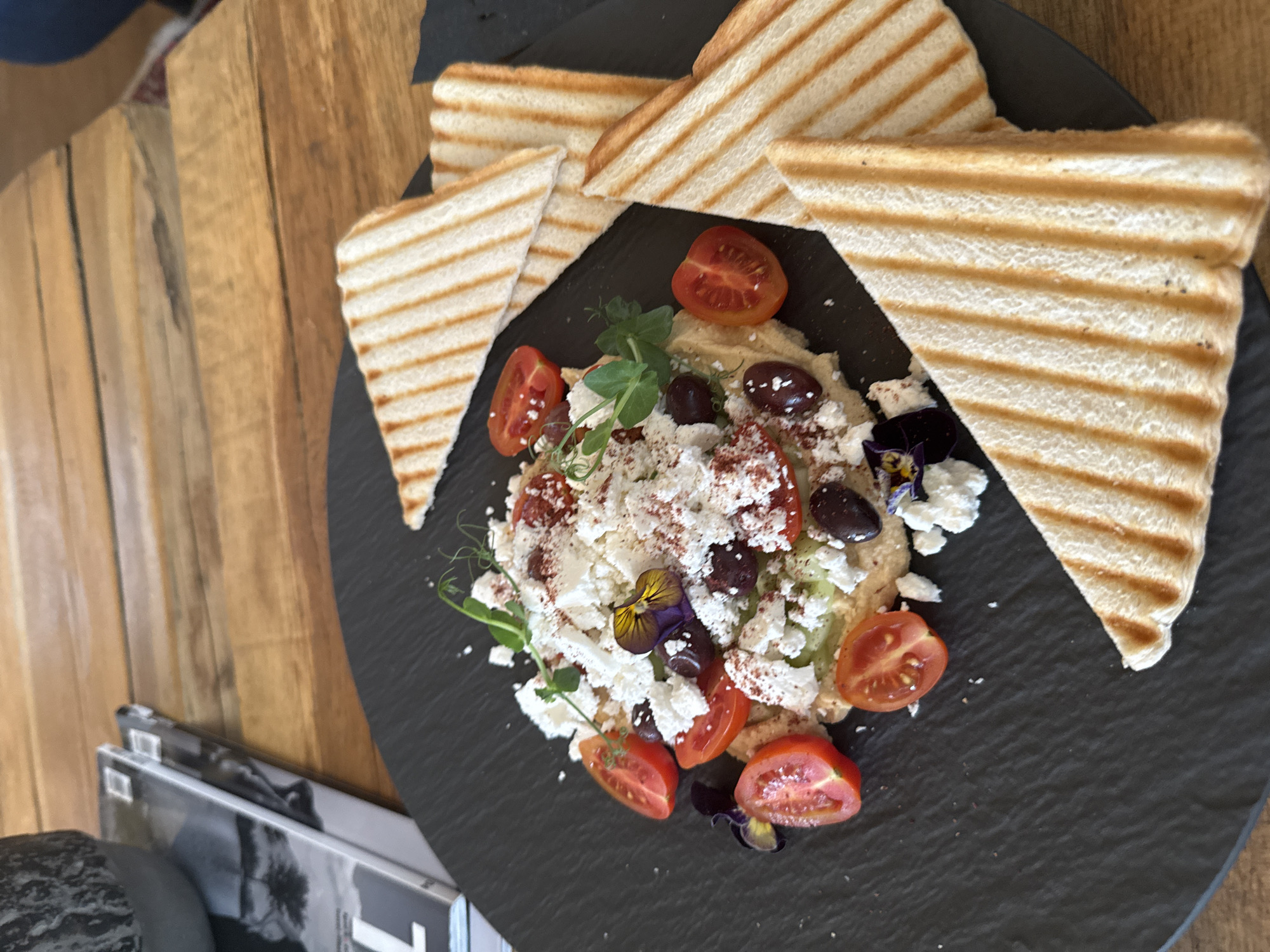 Mediterranean dish with hummus, feta, tomatoes photographed on slate