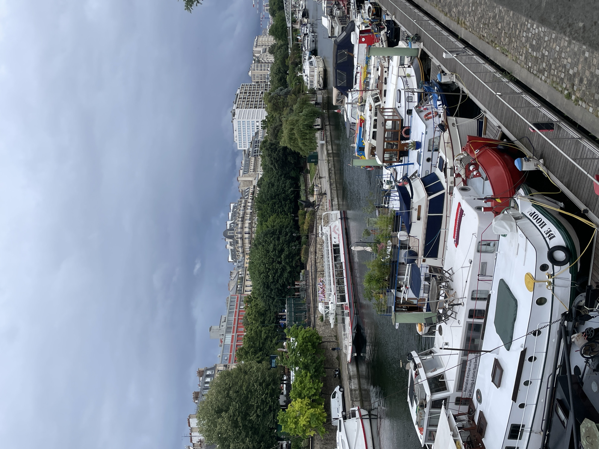 Houseboats line busy Parisian waterway under overcast skies