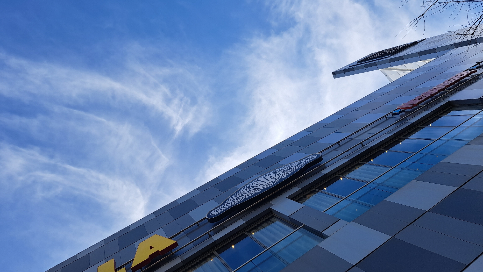 Modern grid-facade building photographed against blue sky with clouds
