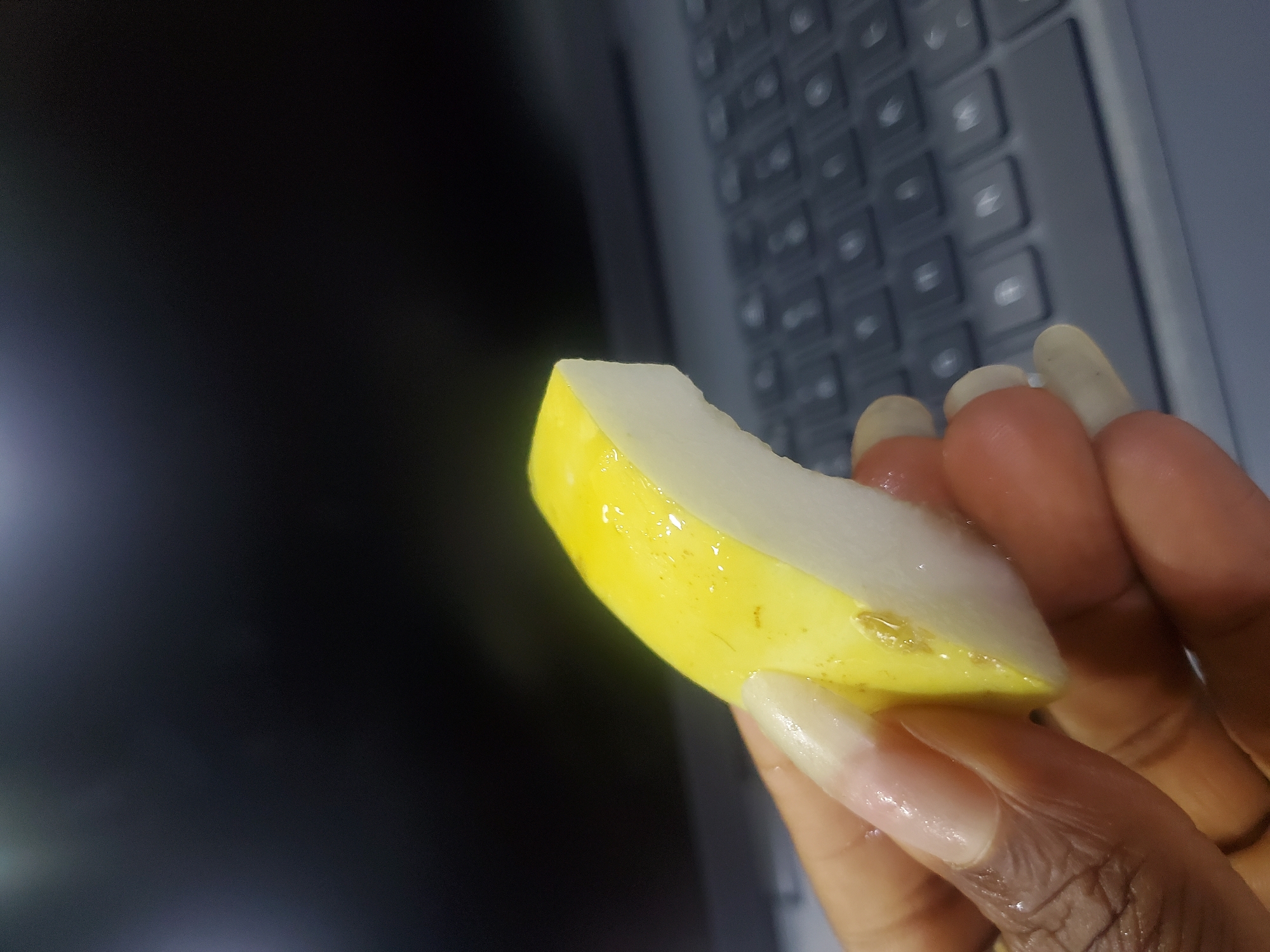 Woman takes fruit break while working at laptop in Nigeria