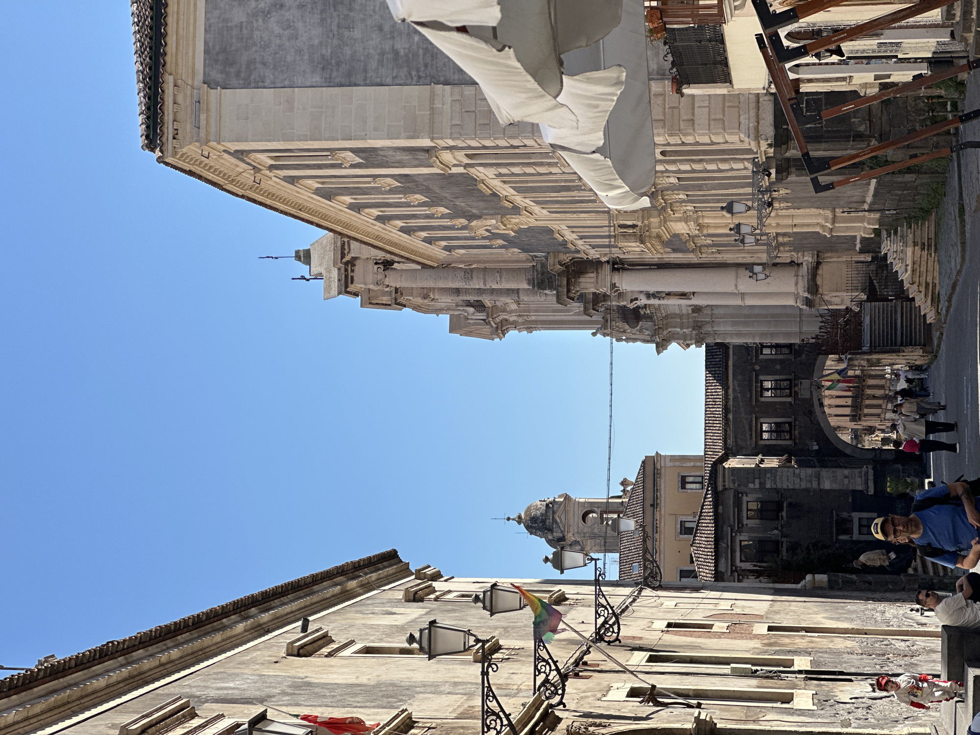 Colorful umbrella-decorated streets bustling with midday life in Catania