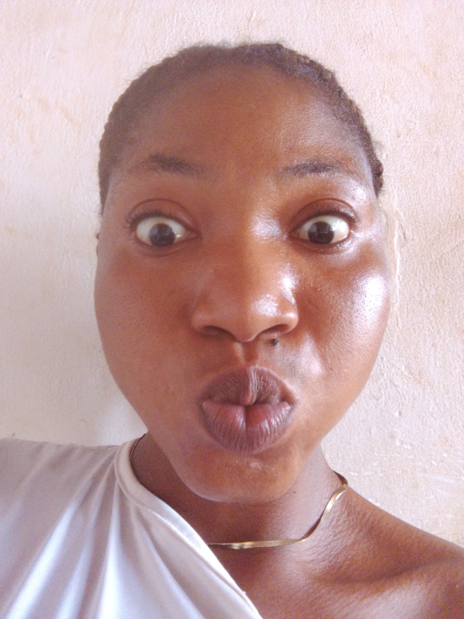 Woman captures indoor selfies in white top and necklace