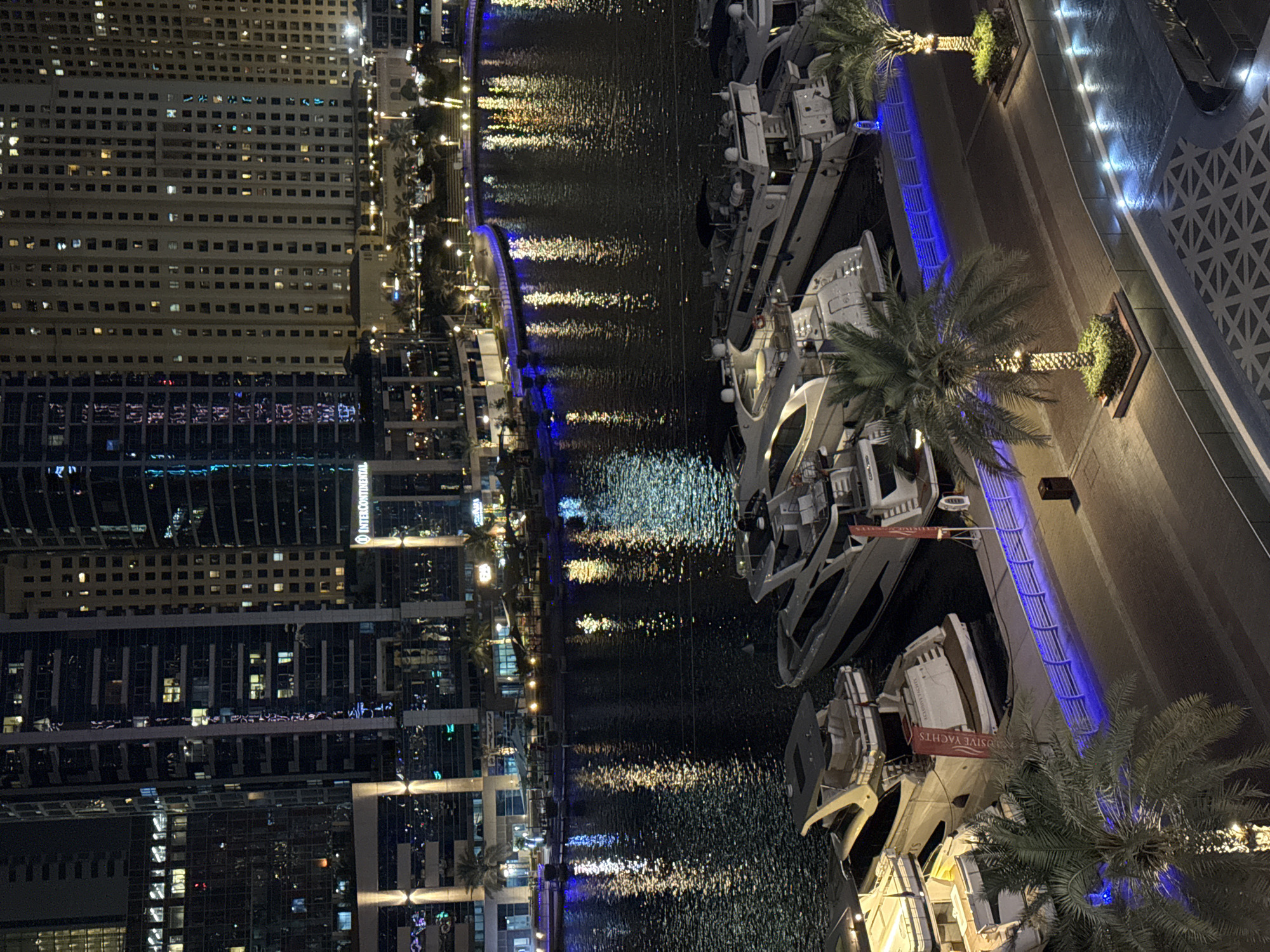 Dubai Marina skyline mirrors across the water at night.