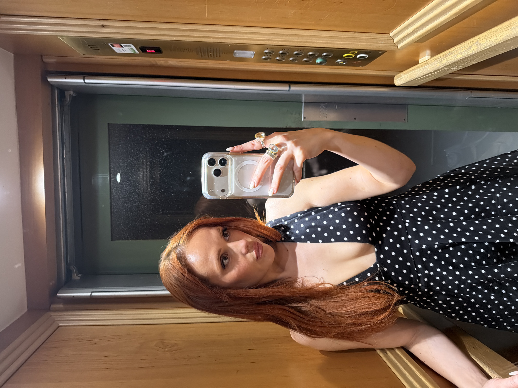 Woman takes selfies in Parisian elevator wearing polka-dot dress