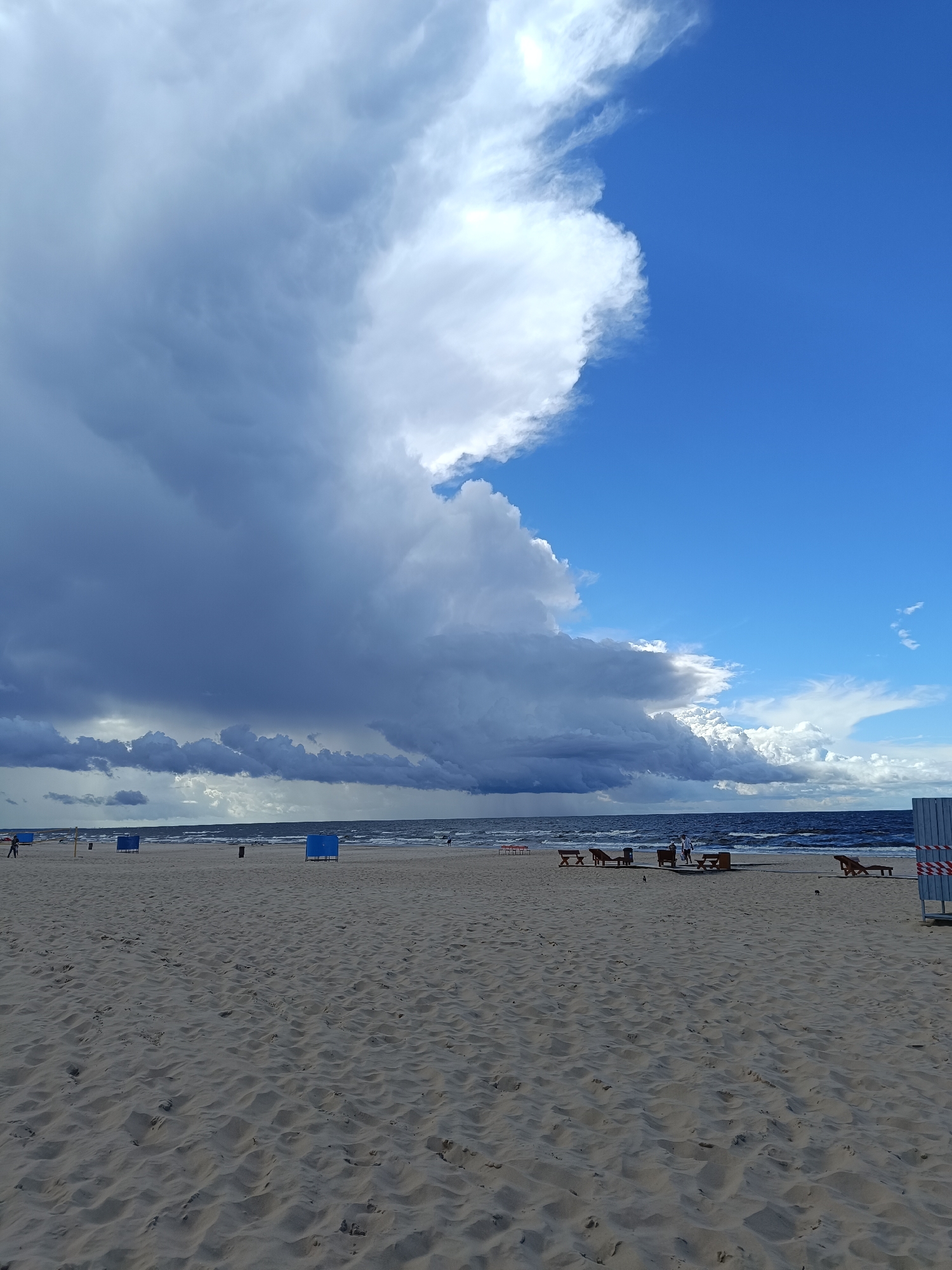 Kitesurfing and beachgoers on a stormy Baltic shore near Riga