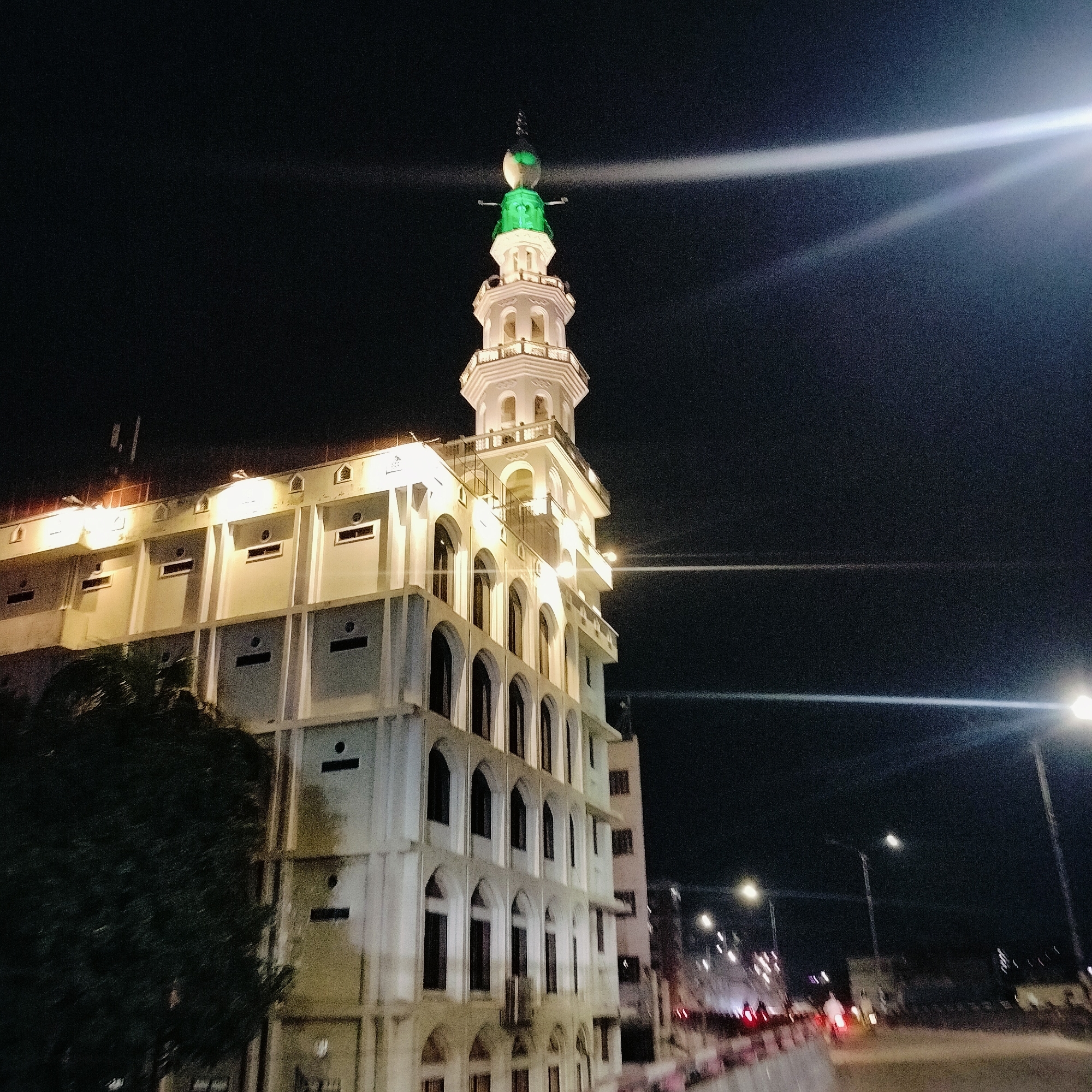 Dhaka after dark: lit minaret and night highway traffic